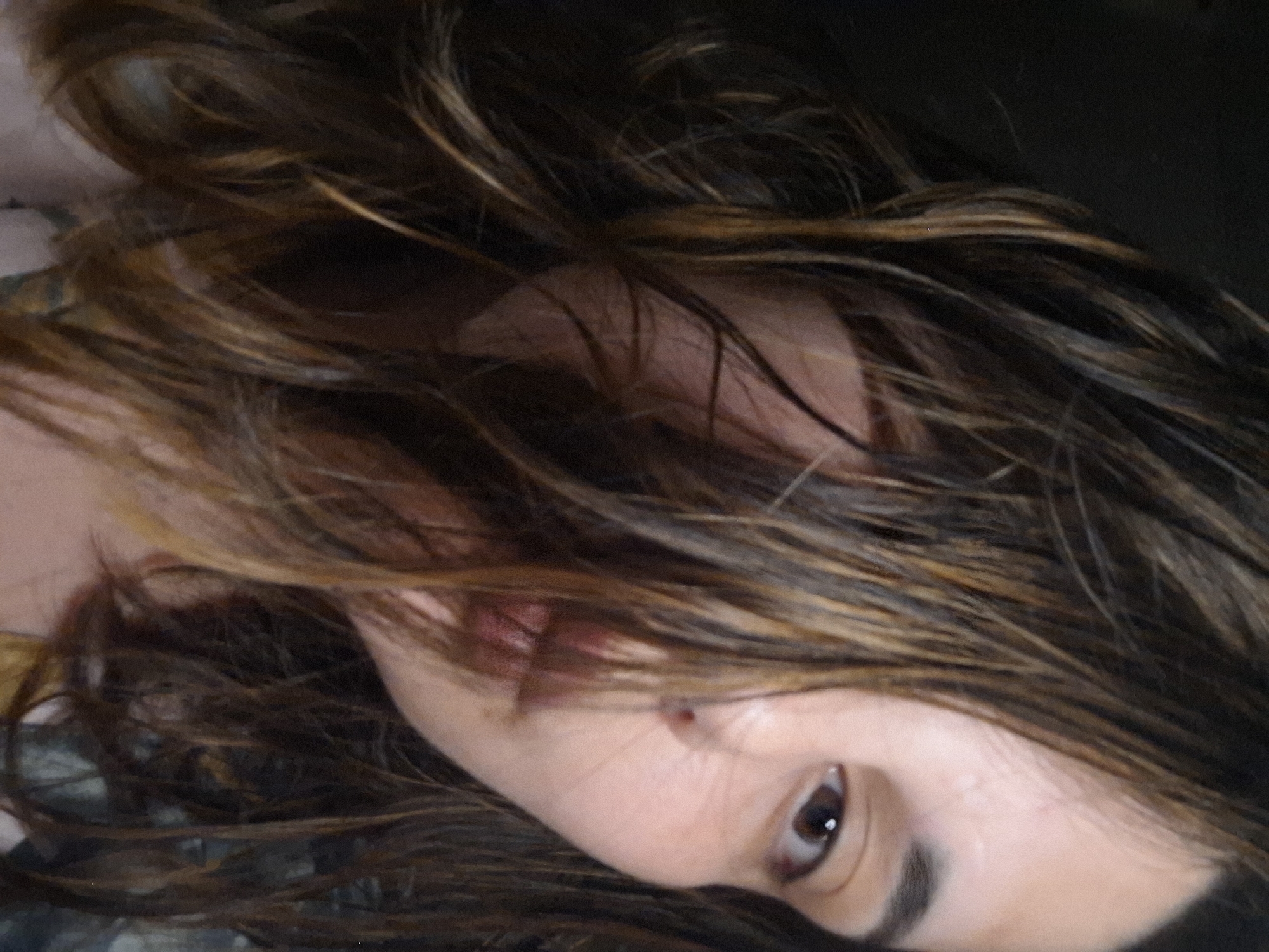 The image depicts a close-up view of a person's face, angled to the side. The person has brown hair with some lighter highlights, which obscures a portion of the face. Only one eye is fully visible; it's brown. Part of the nose and mouth are also visible. The skin tone appears light. No information about the city of Амзя, Russia, or any environmental details is present in the image.