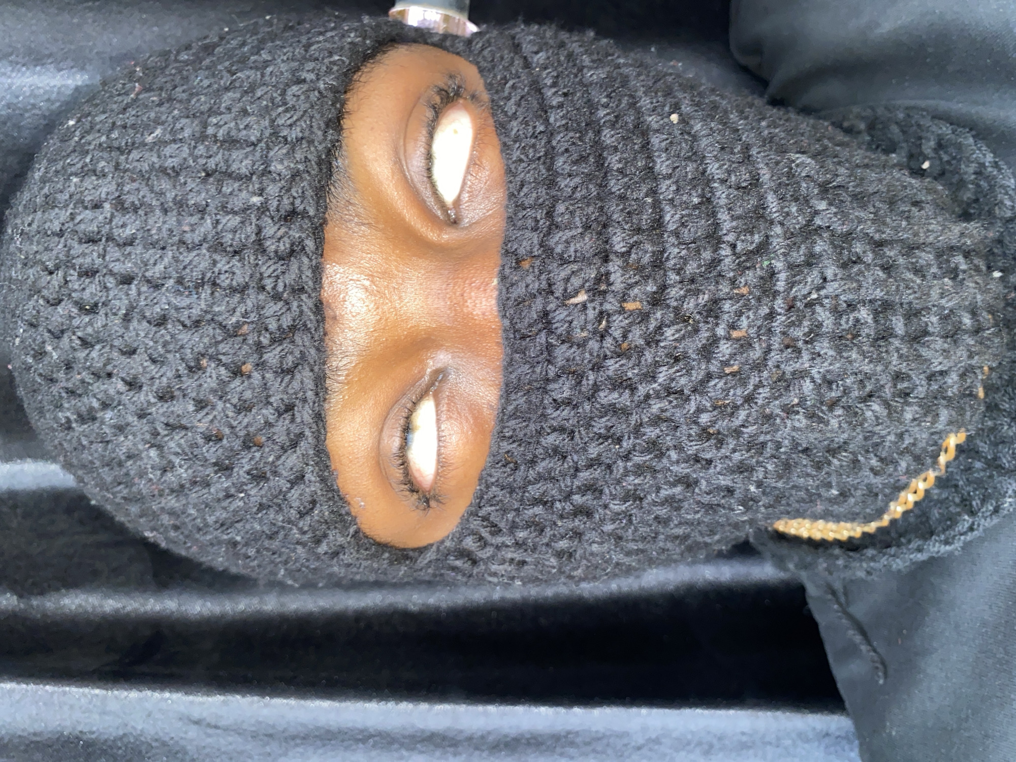 A close-up photograph shows a person's face almost entirely covered by a black, knitted balaclava. Only the area around the eyes and nose is exposed, revealing brown skin. The person's eyes are open, showing white sclera. The balaclava has a slightly coarse, textured appearance. The setting and specific details of the location in Barakin Akawo, Nigeria, are not discernible from the visual information provided.