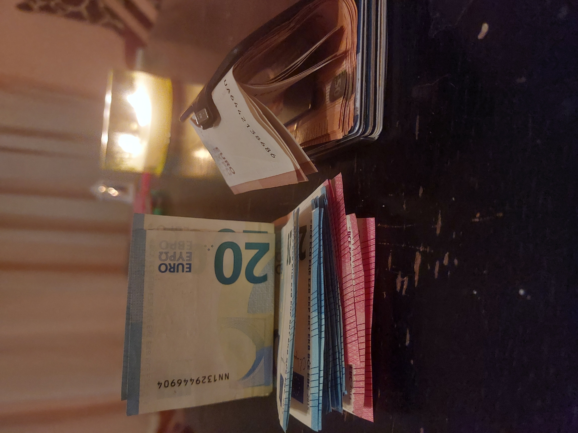 The image shows a wallet containing a stack of euro banknotes on a dark surface. The denominations visible include 20 euro and 50 euro notes. The setting appears to be indoors. There is no information in the image to suggest a location in the city of Tsarevo, Bulgaria.