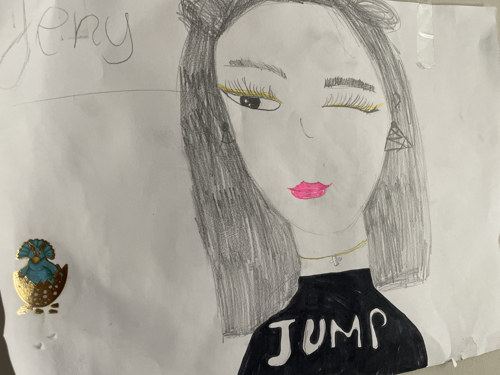This is a photograph of a child's drawing on white paper. The drawing depicts a stylized portrait of a person with dark hair, yellow eyeliner, and bright pink lips. The person is wearing a black shirt with the word "JUMP" written on it in white letters, and a gold necklace with a cross pendant. To the left of the drawing, there is a small, gold-colored sticker of a blue dinosaur hatching from an egg. The word "Jeny" is written in faint pencil at the top left of the paper. The overall impression is that of a creative piece by a child. There is no discernible location in the city of Cahul, Moldova, associated with this image.