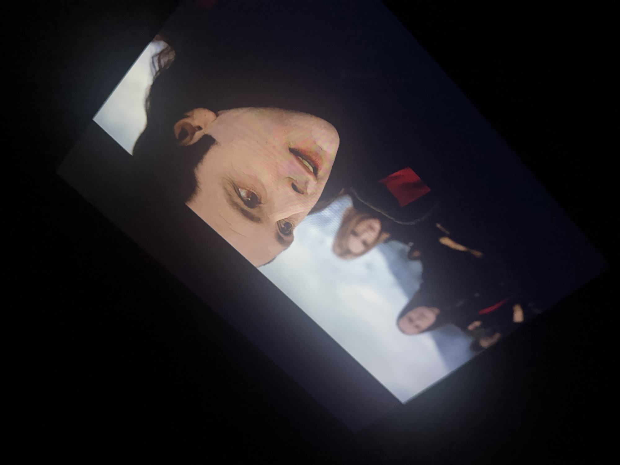 The image shows a screen displaying a close-up of Robert Pattinson's face as Edward Cullen from the film "Twilight", turned at an angle, with other characters visible in the background. The setting is not the city of San Cristóbal, Mexico, but appears to be in a cloudy, outdoor environment, likely filmed on a sound stage or similar location.