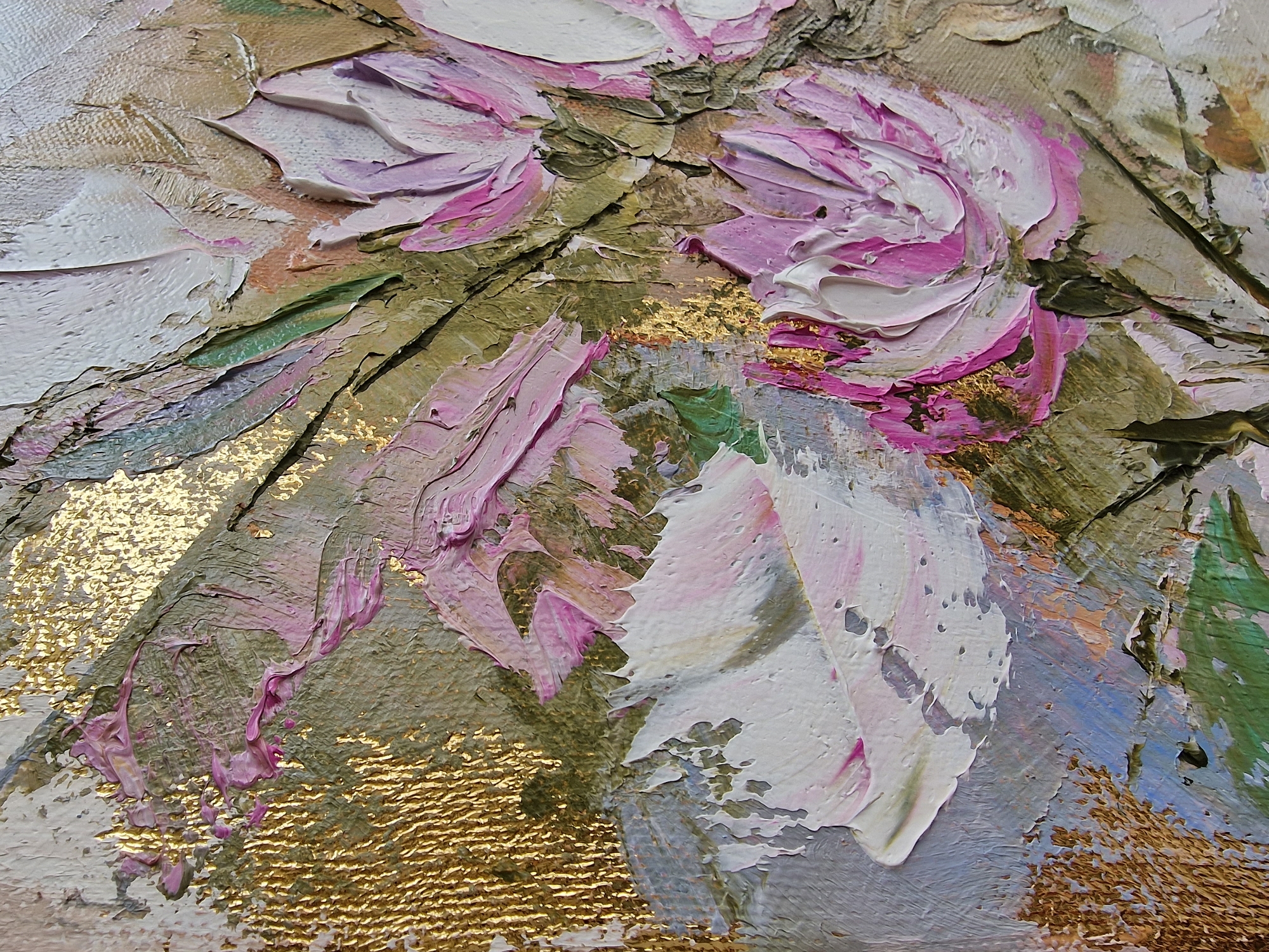 This image is a close-up photograph of an impasto oil painting, characterized by heavy, textured applications of paint and metallic leaf. The artwork depicts abstract floral forms, primarily blossoms, rendered in shades of bright pink, white, and muted beige, set against backgrounds of olive green, light blue, and prominent textured gold. Visible brushstrokes and palette knife marks create significant dimensionality, defining petals and foliage without clear outlines. No human subjects or discernible actions are depicted. This artwork is situated in Veliko Tarnovo, Bulgaria.