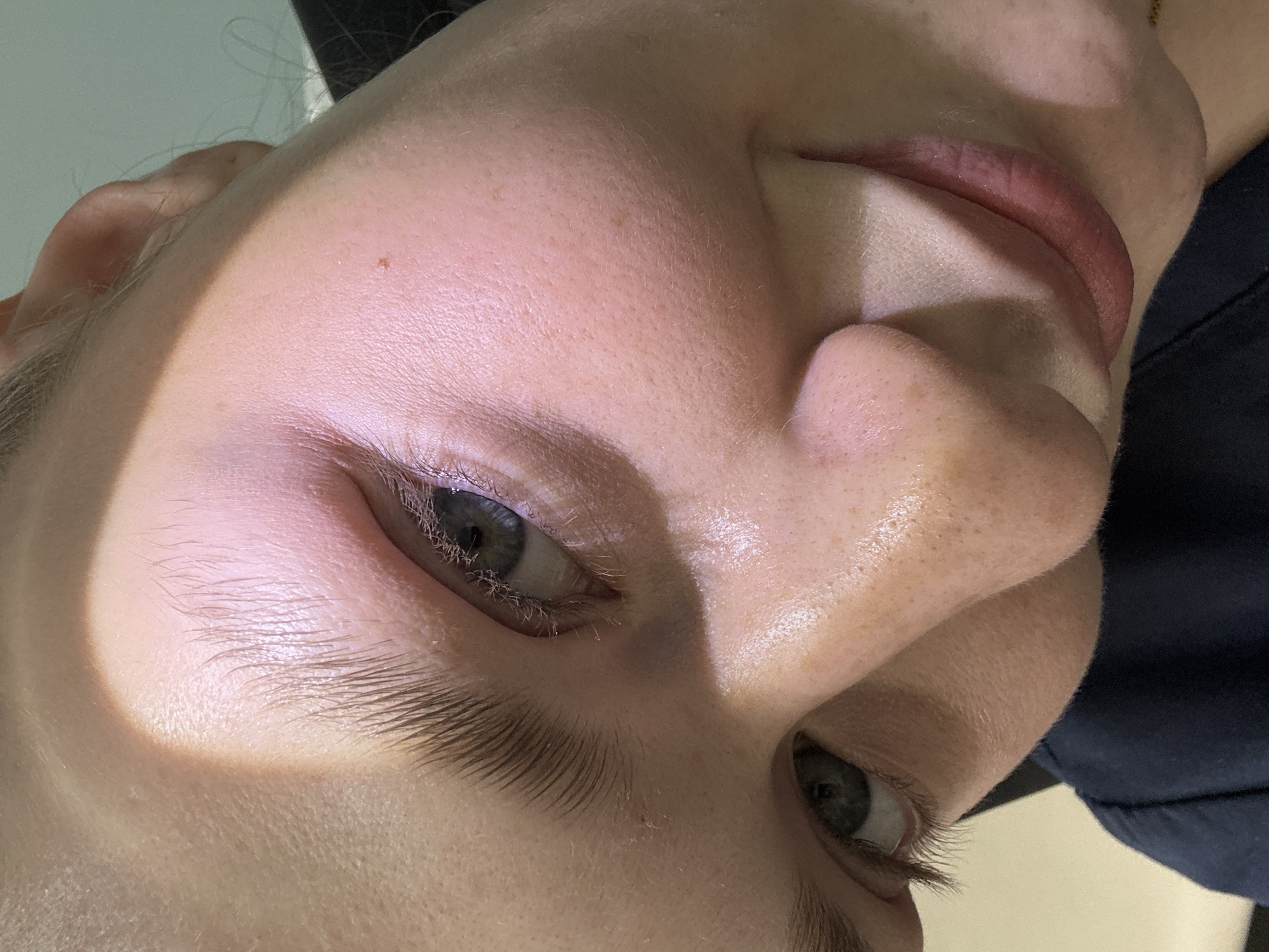Close-up, tilted view of a Caucasian person's face. The person has fair skin, grey eyes, and thick eyebrows. Some facial pores and skin texture are visible. The lips are pink and slightly parted. A mole is visible on the forehead. The person is wearing a dark-colored top. The image provides no context for location, thus the claim that it is located in Kazan, Russia is unsupported.