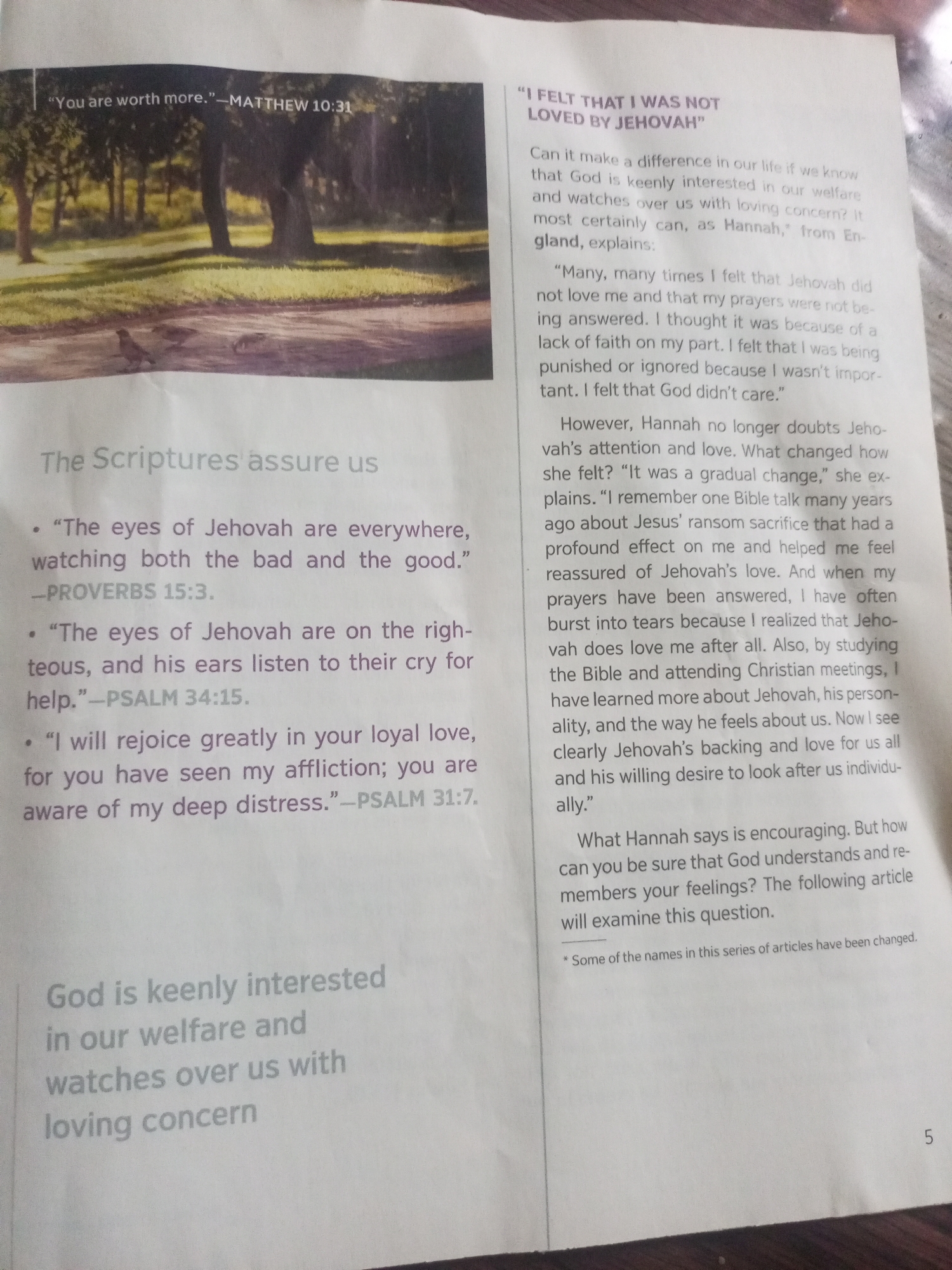 This media file is a photograph of an open book or magazine, displaying text and an image. The image shows a sun-dappled park or wooded area with trees and a paved path. Two birds are visible on the path. The text discusses the concept of God's loving concern for individuals, featuring a personal account from someone named Hannah. It includes Bible verses from Matthew, Proverbs, and Psalms, as well as a narrative about Hannah's journey to feeling loved by Jehovah. The page also contains a footnote stating that some names in the series have been changed and a page number "5" at the bottom right. The overall tone of the text is religious and encouraging. No specific time of day, weather, or location cues beyond the mention of "England" in relation to Hannah are apparent in the image.