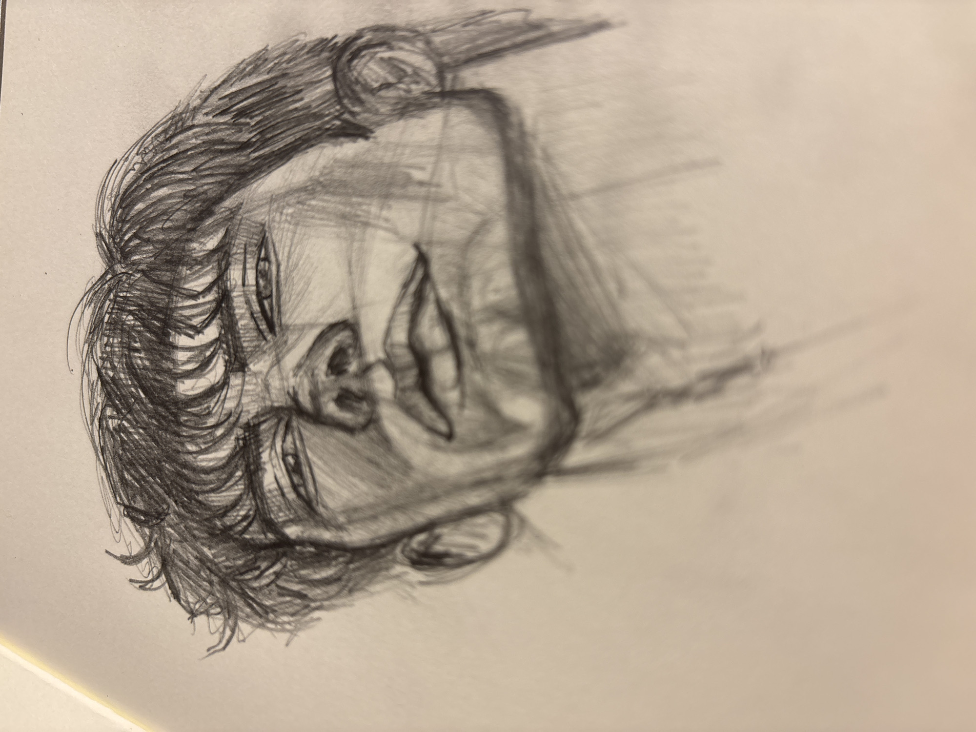 The image is a pencil sketch of a person's head and shoulders. The person is smiling with a wide mouth, their face slightly tilted. The drawing is in shades of gray, with visible pencil strokes creating texture and shading. The person has short, textured hair. The background is plain white paper.
There is no indication of the location being in Izhevsk, Russia, or any other specific location. The sketch is generic and provides no environmental or contextual clues to determine its location.