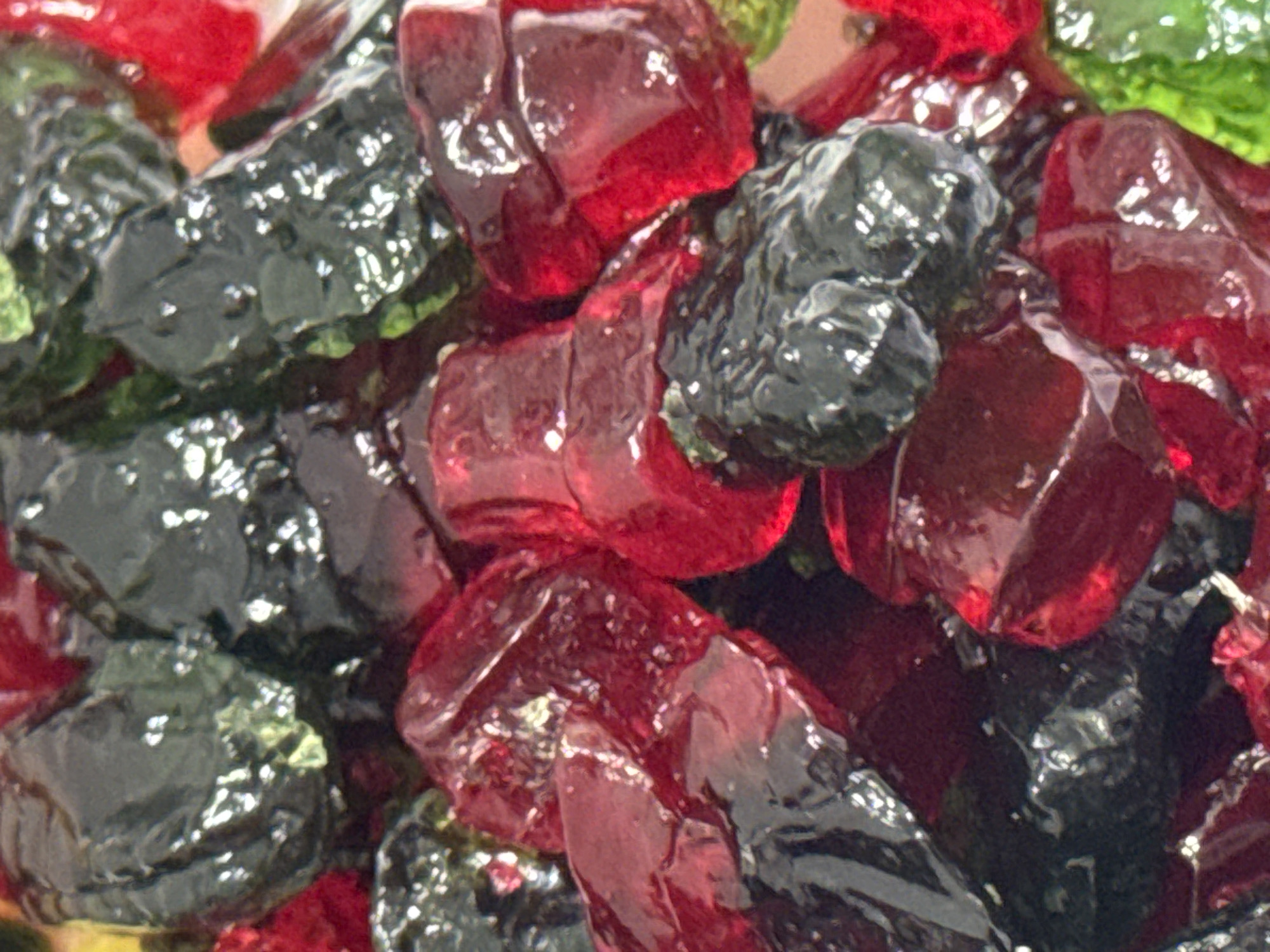 A close-up shot depicts a pile of red and dark green gelatinous candies or gums. No specific details indicate the location in Krasnodar, Russia. There are no people visible, and the only objects present are the candies, with no interactions or actions taking place. The environment appears to be a container of these candies.