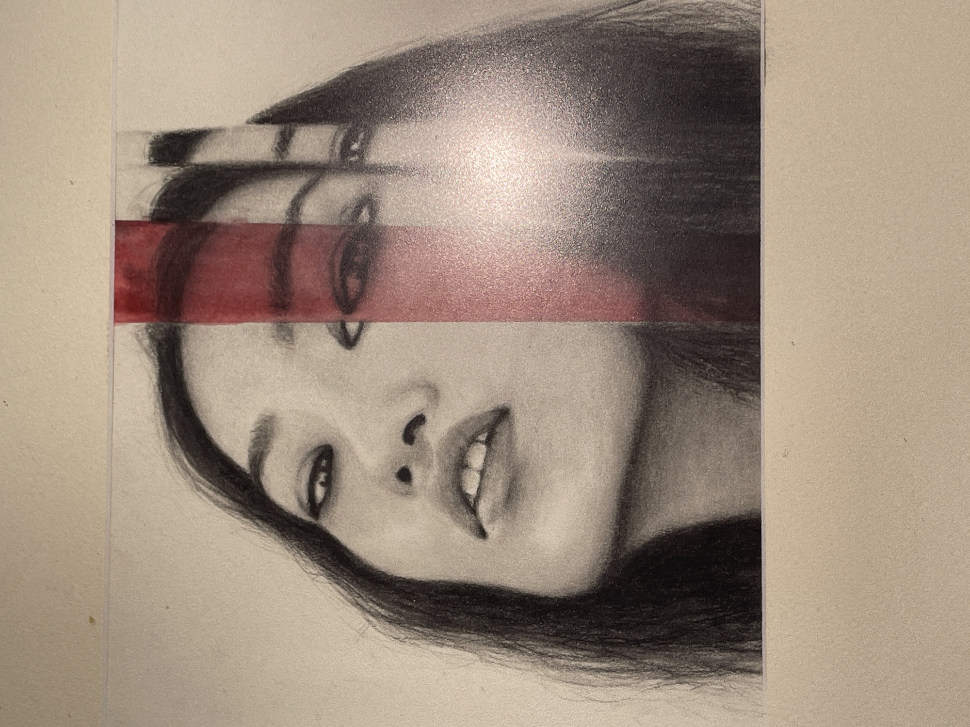 A black and white drawing of a woman's face is presented with a vertical red stripe superimposed over the image, creating a fragmented or layered effect. The woman's head is tilted downwards and her gaze is directed upwards. Her mouth is slightly open, revealing her teeth. Her hair is long and dark, framing her face. The red stripe cuts across her forehead and cheek, obscuring parts of her features and giving the impression of a distorted or broken reflection. The background is a light, textured surface, likely paper. The overall presentation suggests an artistic composition rather than a photograph of a real-world scene. There is no information about a specific city or location.