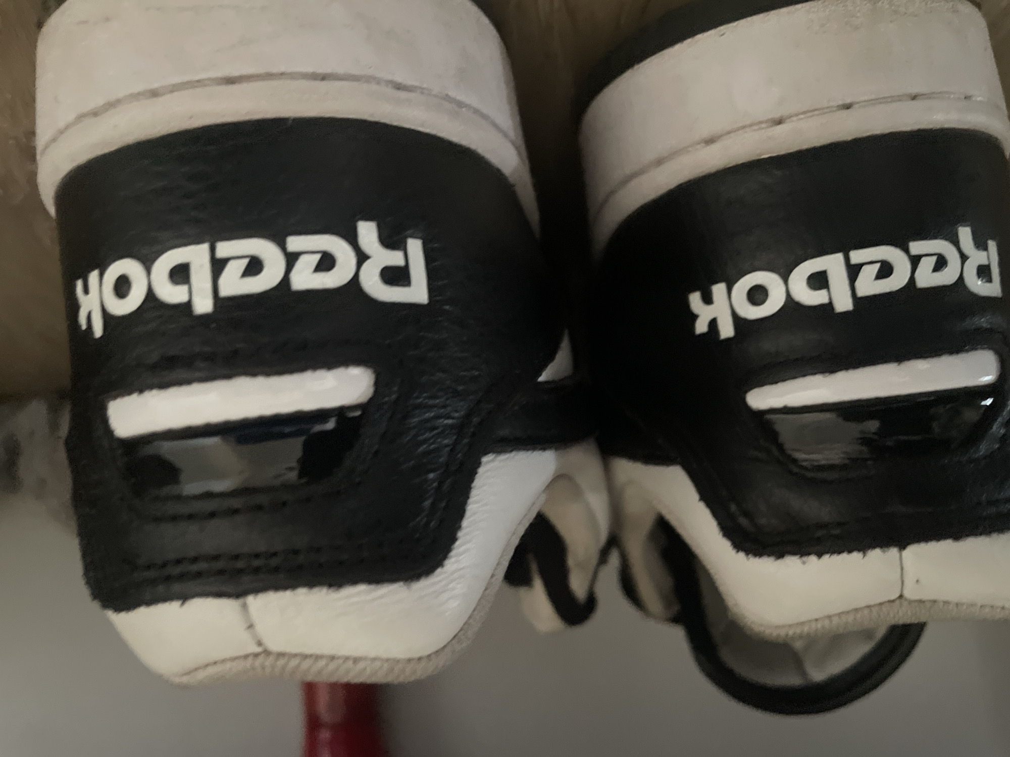 The image shows the backs of two black and white Reebok shoes. The location is not discernible from the image.