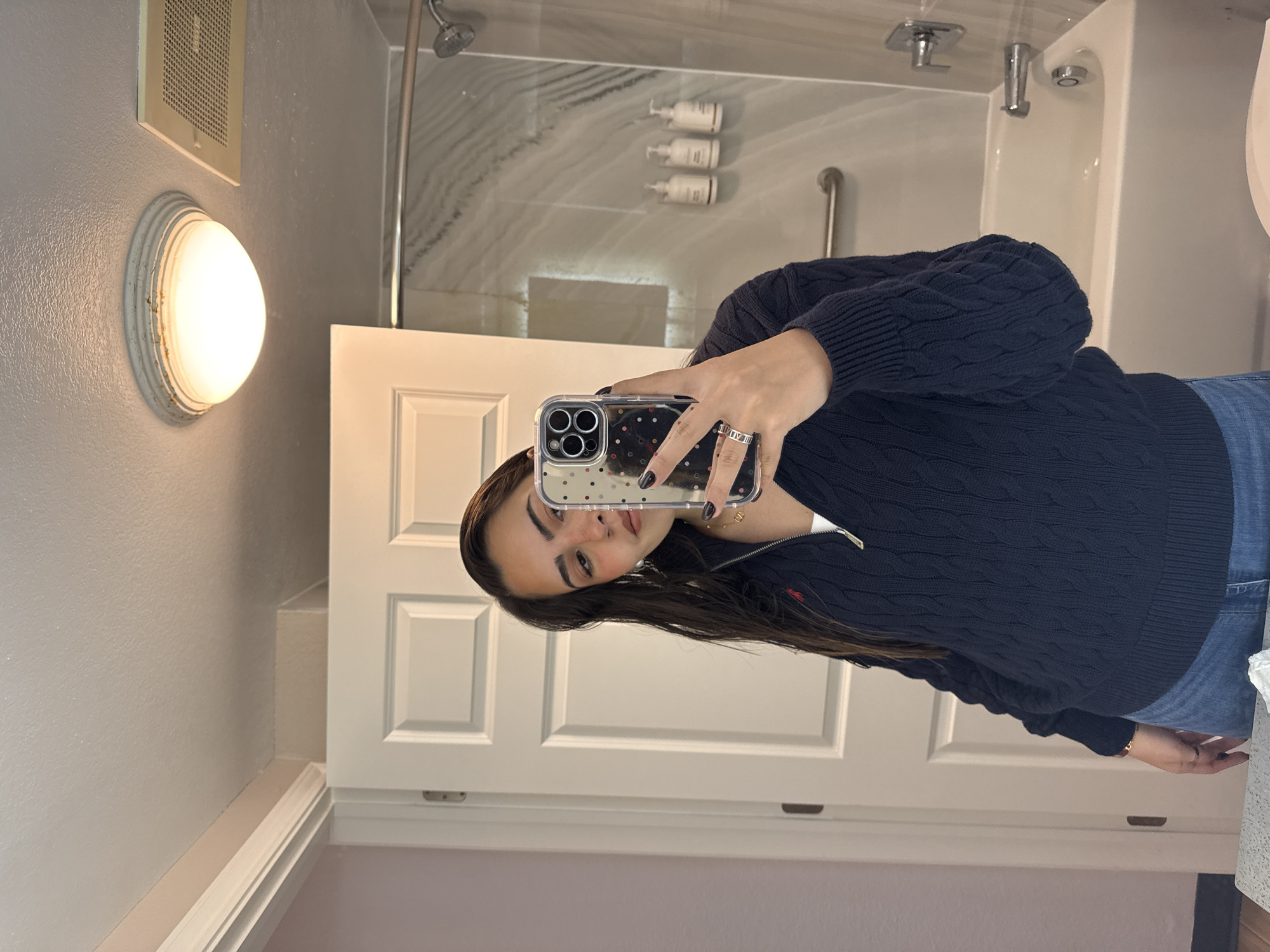 A young woman is taking a selfie in a bathroom. The bathroom features a white door, a shower with a marble-patterned surround, and a light fixture on the wall.
Without additional information, it is not possible to determine the exact location within San Antonio, USA.