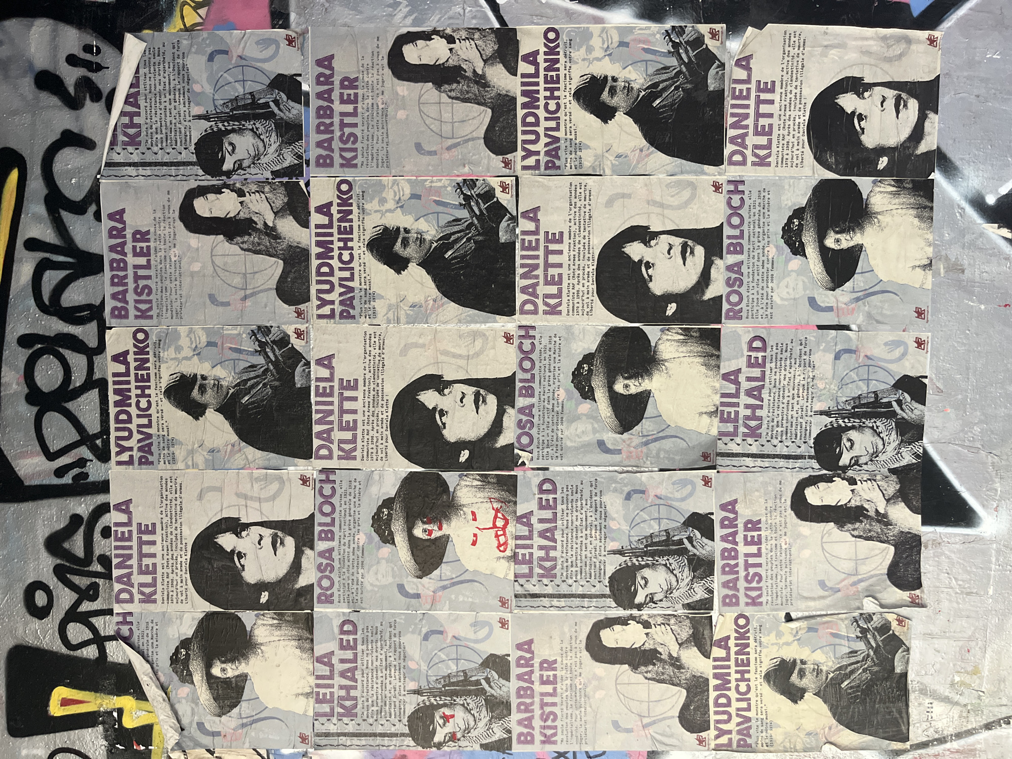 The image shows a wall covered with posters in Geneva, Switzerland. The posters are of women, some holding guns, with text in French. The posters appear to be propaganda or political statements. The wall itself is covered in graffiti, suggesting an urban environment. The posters are arranged in a grid-like pattern, with some overlap and damage.