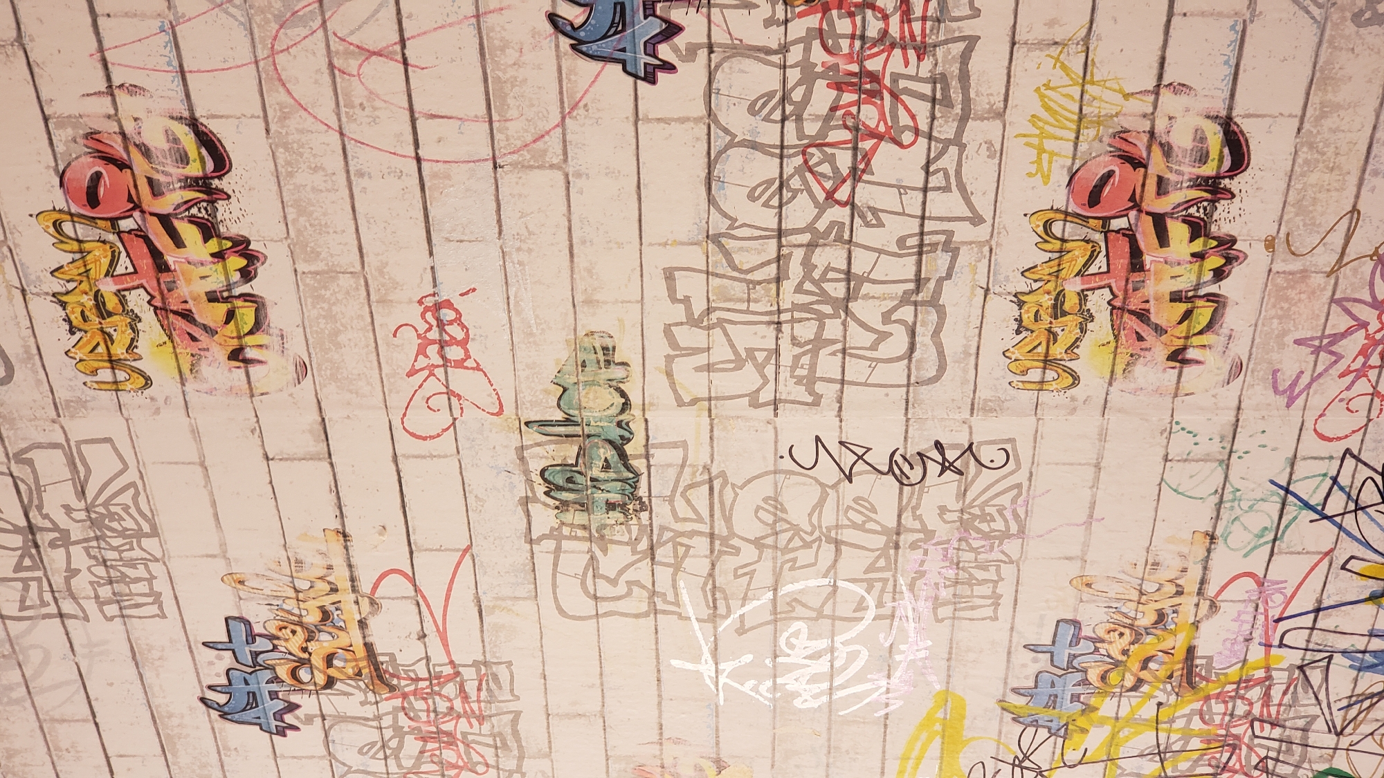 The image shows a wall covered in graffiti. The graffiti is in various colors and styles, with some pieces overlapping others. The wall appears to be made of bricks, and the overall scene suggests an urban environment. The graffiti includes tags, bubble letters, and more elaborate designs. Some of the graffiti is faded, while other pieces are bright and new. There are no people or animals visible in the image. The context of Bratislava, Slovakia, is not evident from the image itself, as graffiti art is common in many cities worldwide.