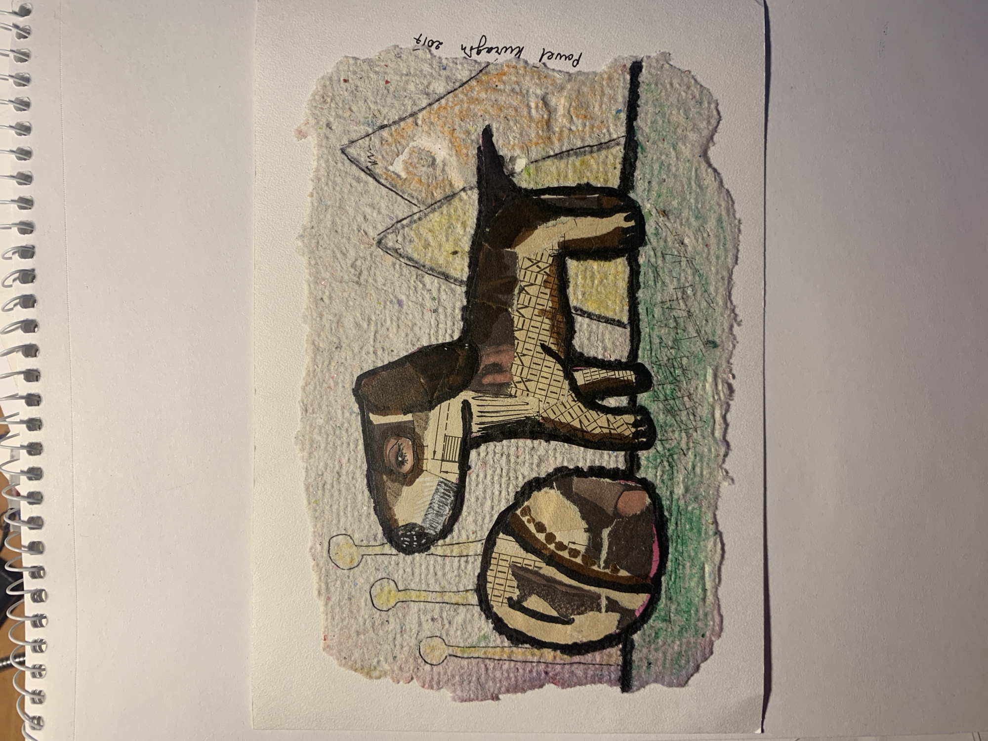 This media file features a collage artwork on textured, off-white paper. The artwork depicts a stylized dog-like figure in shades of brown and black, with collage elements of text and patterns. The dog's head is on the left, with a prominent eye. Its body is elongated, with legs tucked beneath. Below the dog is a circular object, also made of collage, which appears to be a ball or toy. Three yellow, stick-like shapes extend from beneath the dog and ball. The background is a mix of abstract colors, including green, yellow, and pink, with some scribbled lines.
Visible text in black ink at the top right reads: "Pawel Kurash 2017".
The artwork is presented on a white background, with a spiral-bound notebook visible on the left edge of the image. The lighting suggests it is indoors, likely in daylight. The overall mood of the artwork is whimsical and abstract. No specific scene, setting, or event is depicted beyond the stylized elements of the collage itself. The location context provided is Sergeevo, Russia, but there are no visual cues within the image to confirm this.