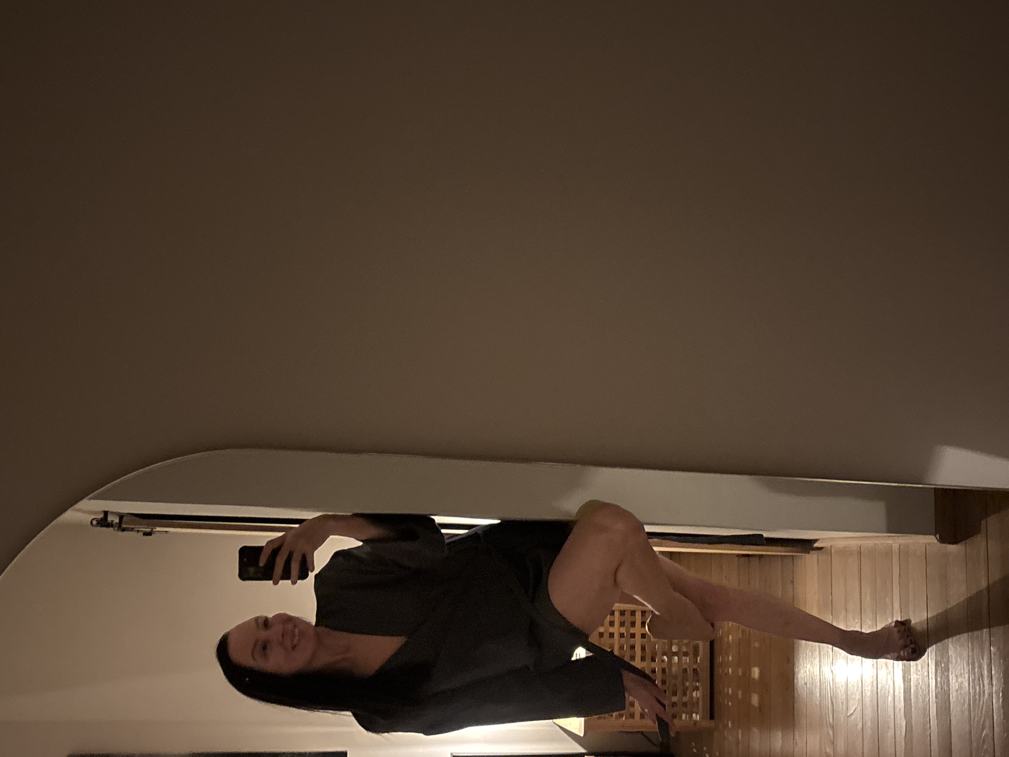A woman with long dark hair is visible in a selfie taken in a mirror. She's wearing a dark robe or jacket. The background shows a room with wood paneled walls. No information indicates the location is in the city of Chaikovsky, Russia.