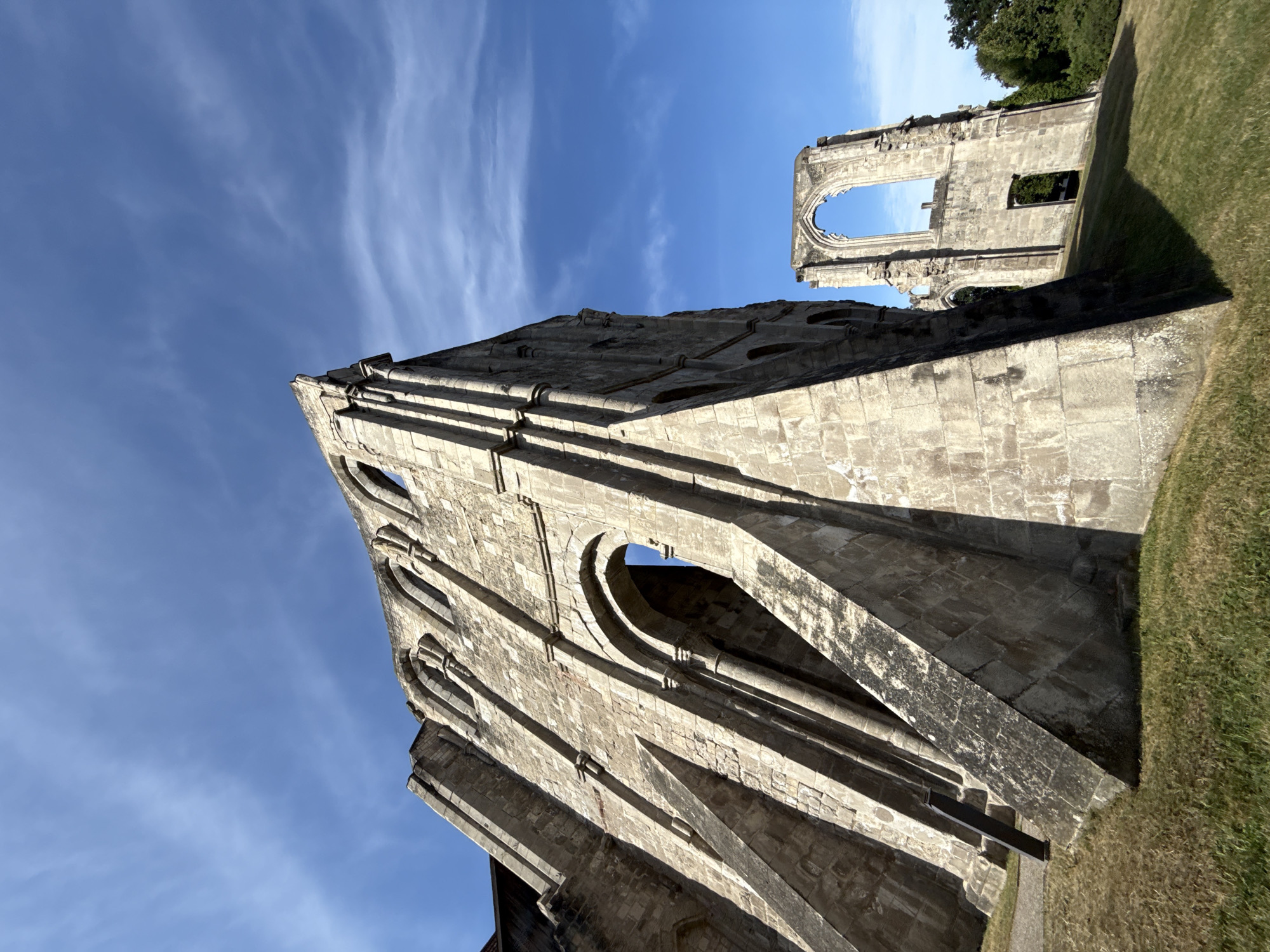 This image shows the ruins of the Walkenried Abbey in Walkenried, Germany. The ruins are made of stone and are overgrown with grass. The sky is blue and there are some clouds. The ruins are a popular tourist attraction and are a UNESCO World Heritage Site. The Abbey was founded in 1137 by Cistercian monks and was one of the most important Cistercian abbeys in Germany. The Abbey was dissolved in 1546 during the Reformation and fell into ruin.