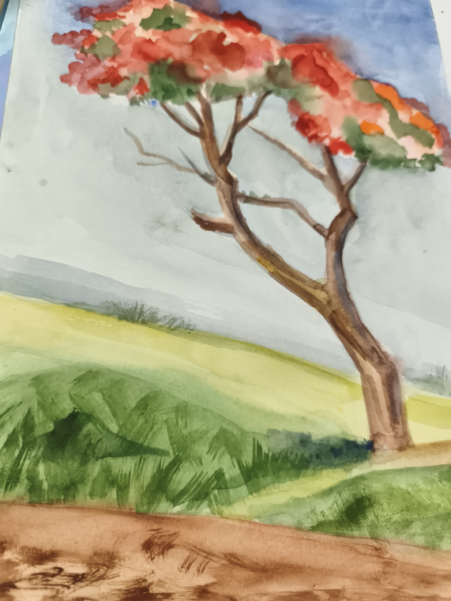 This is a watercolor painting depicting a tree with vibrant red and green foliage against a pale blue and gray sky. The tree has a brown trunk and branches. In the foreground, there are rolling hills rendered in shades of green and yellow, with some brown brushstrokes at the very bottom suggesting earth or a path. The painting has a soft, impressionistic style. There is no discernible location in the city of Saint-Denis, France, depicted in this artwork.