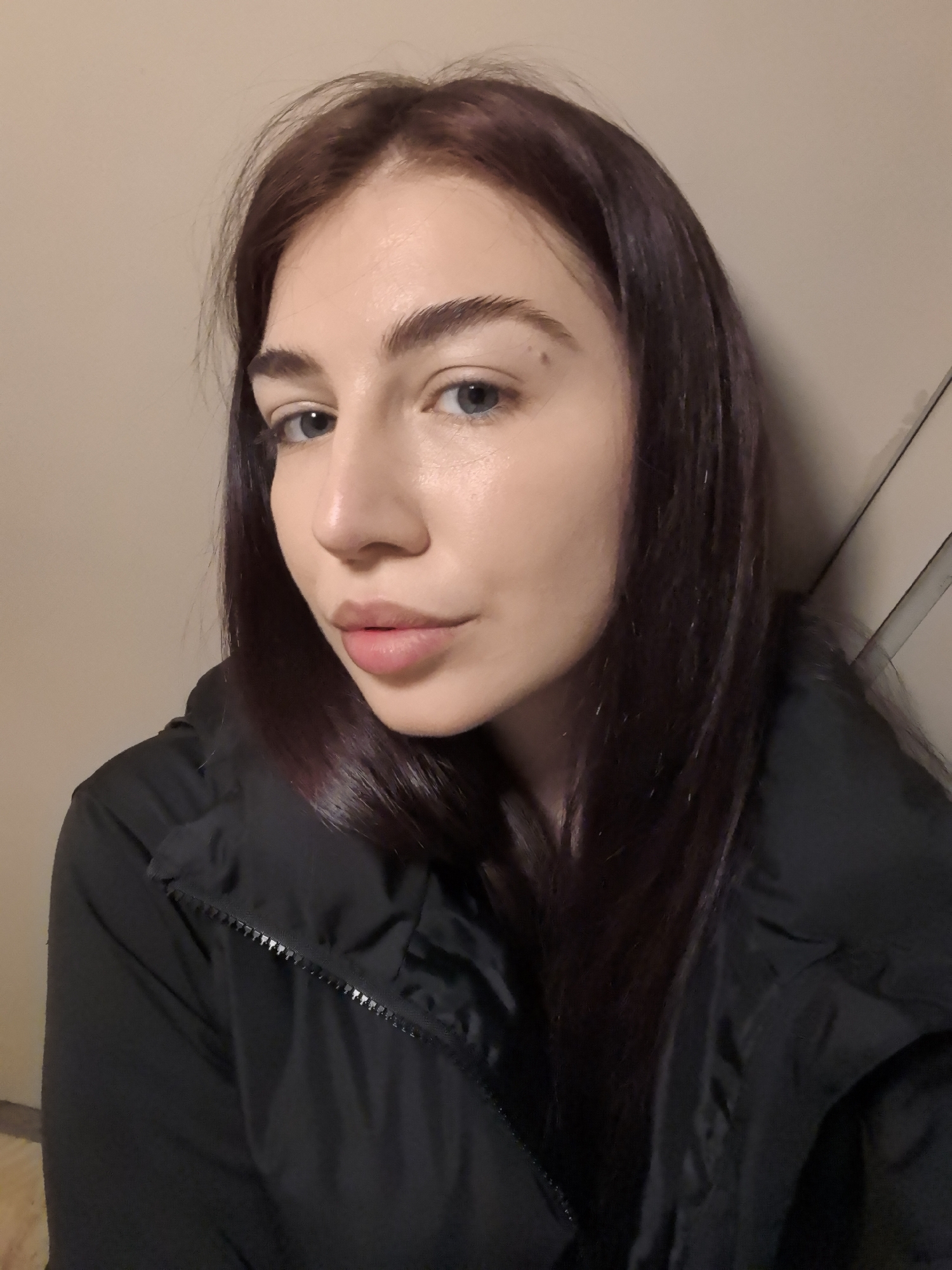 A close-up shot of a fair-skinned woman with dark auburn hair and blue eyes. She is wearing a black jacket. The background appears to be a plain, neutral wall. The lighting is soft and diffused. There are no immediate indicators to suggest this image was taken in Stara Zagora, Bulgaria.