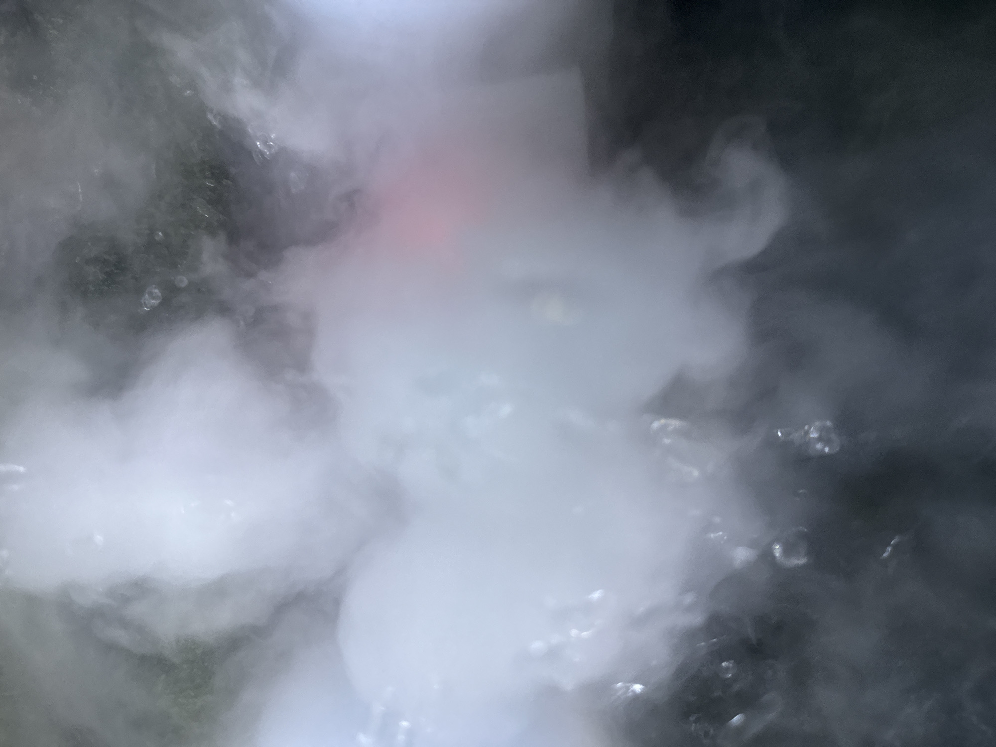 The image shows a close-up view of water, possibly boiling, with significant steam or vapor obscuring much of the scene. Bubbles are visible within the water. The overall color palette is dominated by shades of grey and white, with a possible faint red hue in the upper center. The specific location in Bac Nha Trang Ward, Vietnam cannot be determined from the visual information provided.