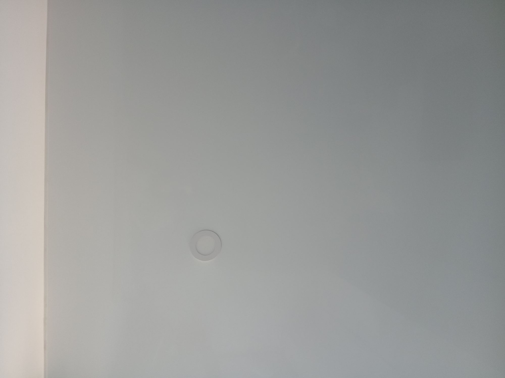 A white ceiling with a round LED light fixture is observed. The left side of the image shows a vertical wall meeting the ceiling. There is no evidence to suggest the location in the city of Batumi, Georgia.
