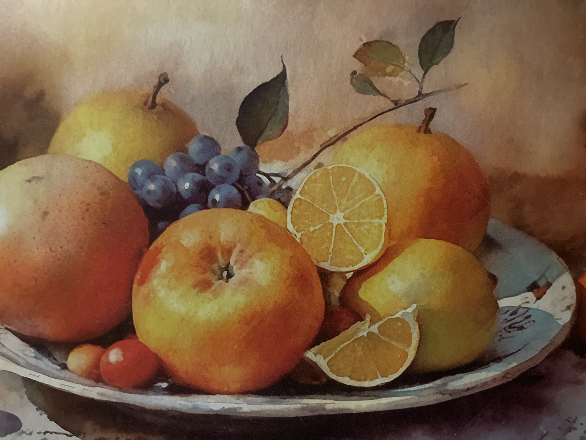 The image is a close-up, watercolor-style painting of a fruit still life. The arrangement includes a large grapefruit or orange, several apples, pears, grapes, and slices of orange. The fruits are depicted in a bowl or platter with a textured, light-colored interior. A branch with a few leaves extends into the frame from the right. The background is a soft, blended wash of warm tones. There are no people or actions depicted in the image. The image does not provide any information that would allow for the determination of a location in Minsk, Belarus, or any other city.
