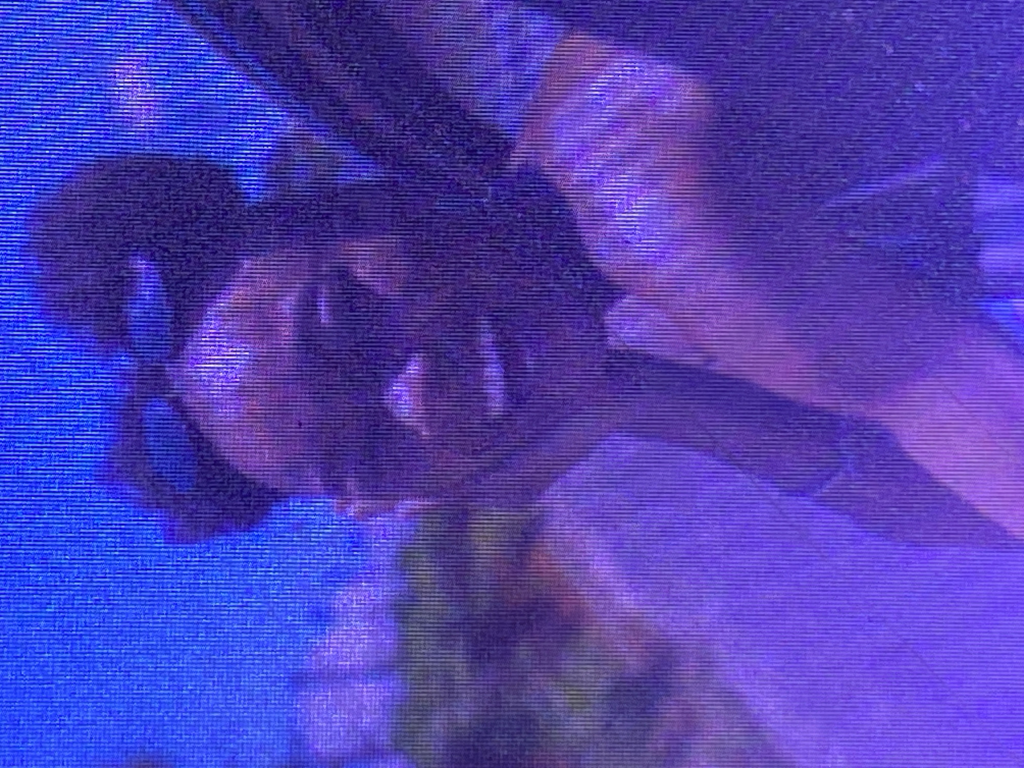 The image is a low-resolution, grainy, and distorted photograph with a dominant purple and blue color palette, suggesting it might be a screen capture or a poorly taken photograph. The image appears to be rotated.
The primary subject appears to be a person, possibly a woman, partially visible. Her face is the most discernible feature, with what seems to be dark hair pulled back, and a hand reaching towards her face or head. The lighting is dim and dramatic, with strong highlights and shadows, suggesting an artificial lighting environment, possibly a stage or a dimly lit room.
The activity or event taking place is unclear due to the poor quality of the image. However, the pose of the visible person and the lighting suggest a performance, a photoshoot, or a candid moment captured during an event. The background is abstract and blurred, with hints of other figures or objects that are not clearly identifiable. There are no discernible text elements in the image. The overall impression is one of a visually obscured, perhaps artistic or dramatic, scene. The mention of "Ikorodu, Nigeria" provides a geographical context, but no specific visual cues within the image directly confirm this location.