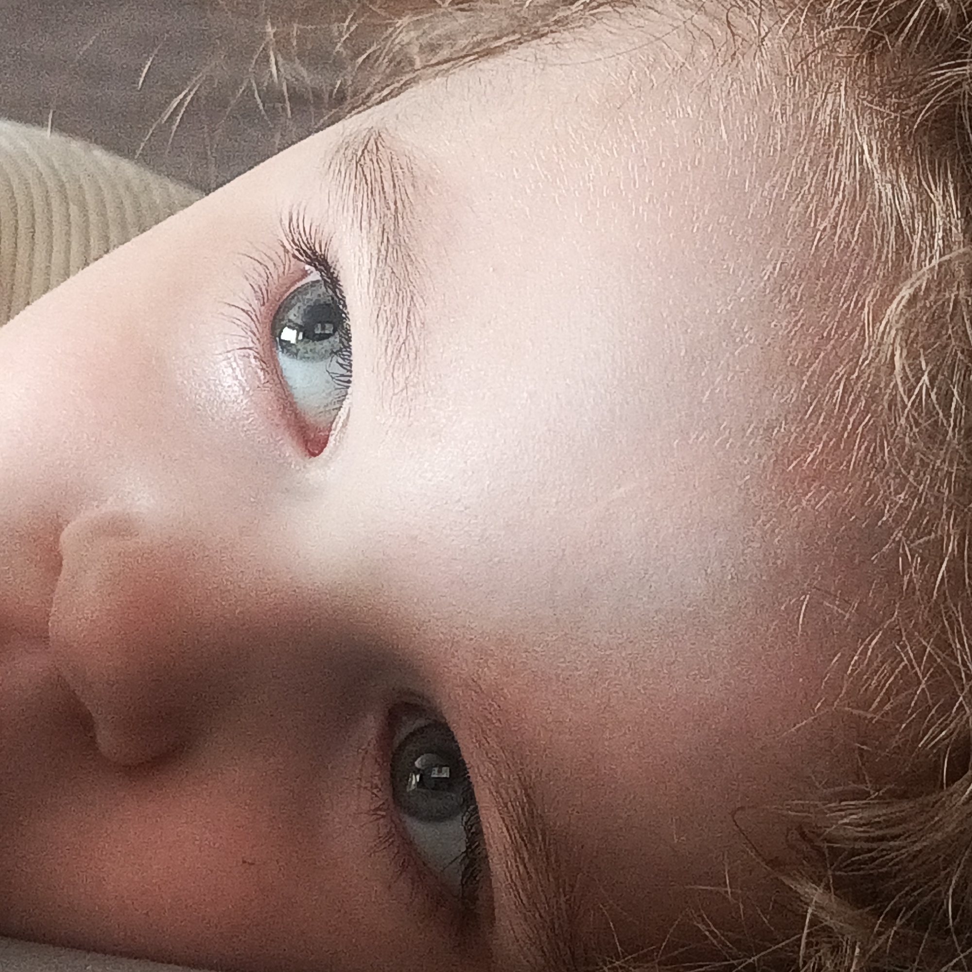 A close-up of a child's face, focusing on their eyes and facial features. The child has light skin, blonde hair, and blue eyes. The image is tightly cropped, emphasizing the details of the skin, eyelashes, and irises. The child appears to be looking upwards. There is no information available in the image to determine the location as being in Марковский, Russia. The image contains no information about actions, interactions, or the environment.