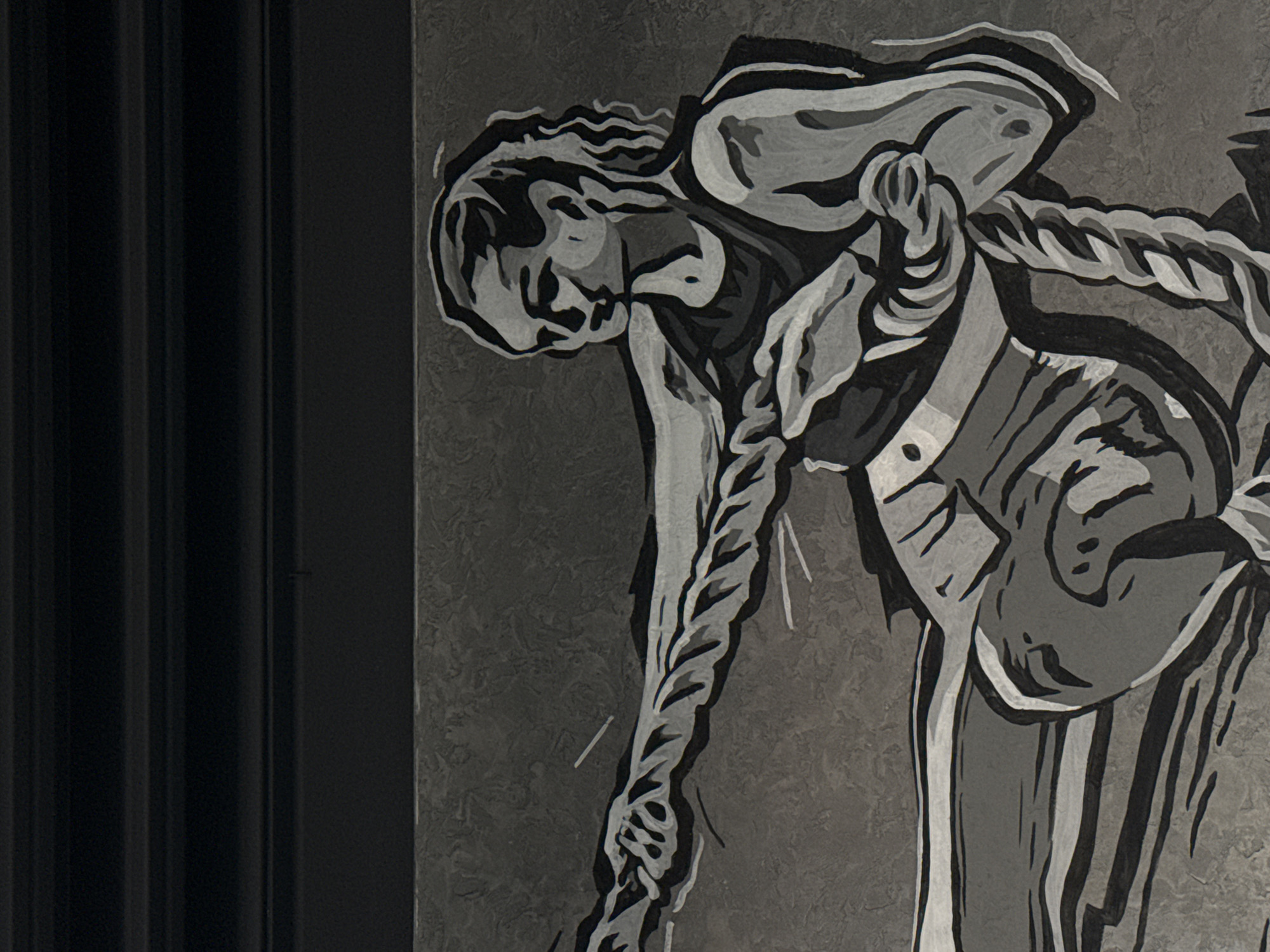 The image is a grayscale depiction of a figure, possibly a painting or mural on a textured wall, located in Votkinsk, Russia. The figure is hunched over, with what appears to be a rope or braid extending from their shoulder down towards the bottom of the frame. They are wearing some sort of garment, possibly with a satchel or bag across their chest. To the left of the painting, there is a dark, vertically-striped structure or wall.