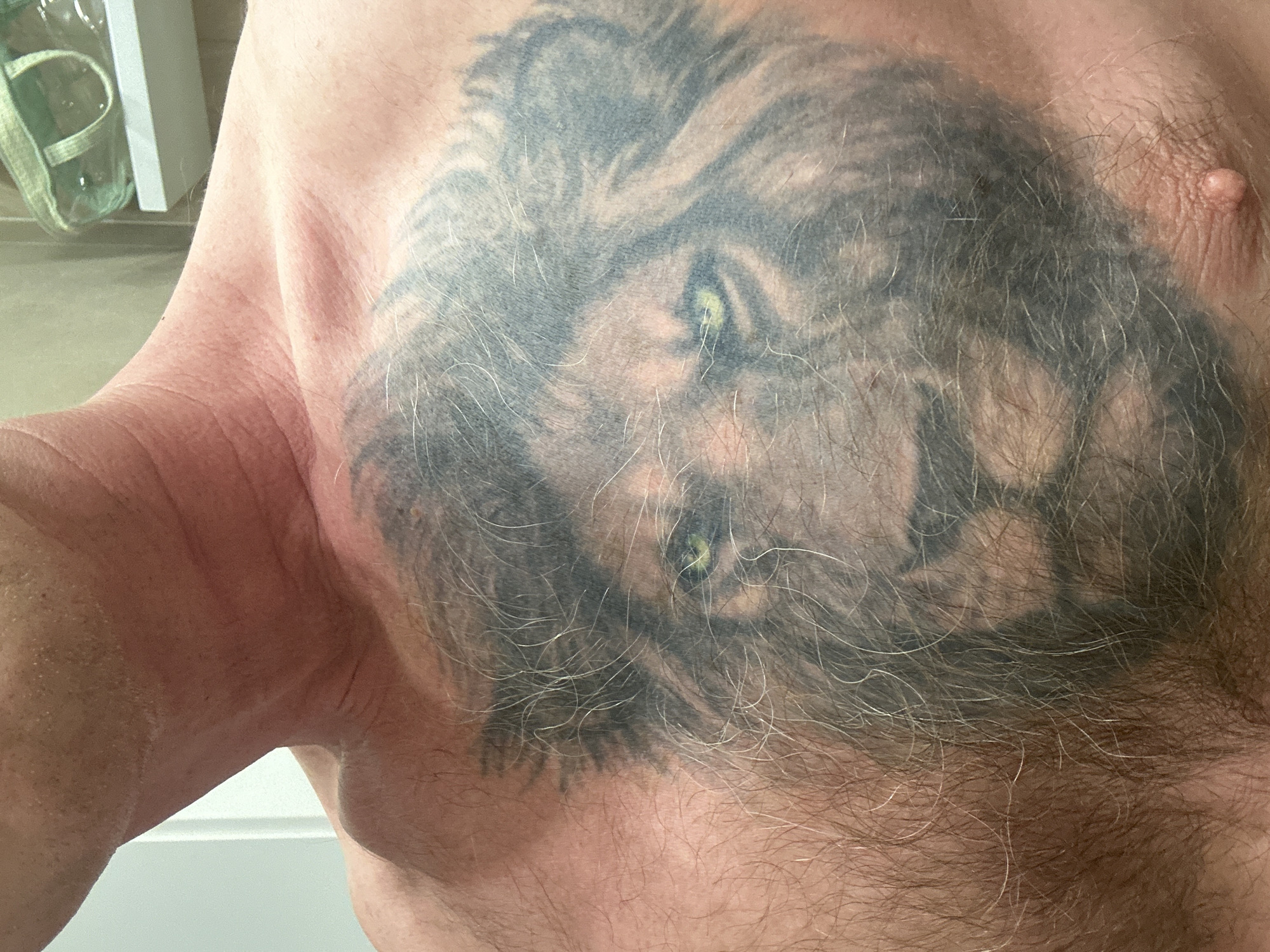 A close-up image shows a fair-skinned, hairy male torso. The chest features a large tattoo of a lion's head, with visible green eyes. A nipple is visible on the right side of the image. The context of the location in the city of Oryol, Russia is unknown from the visible details.