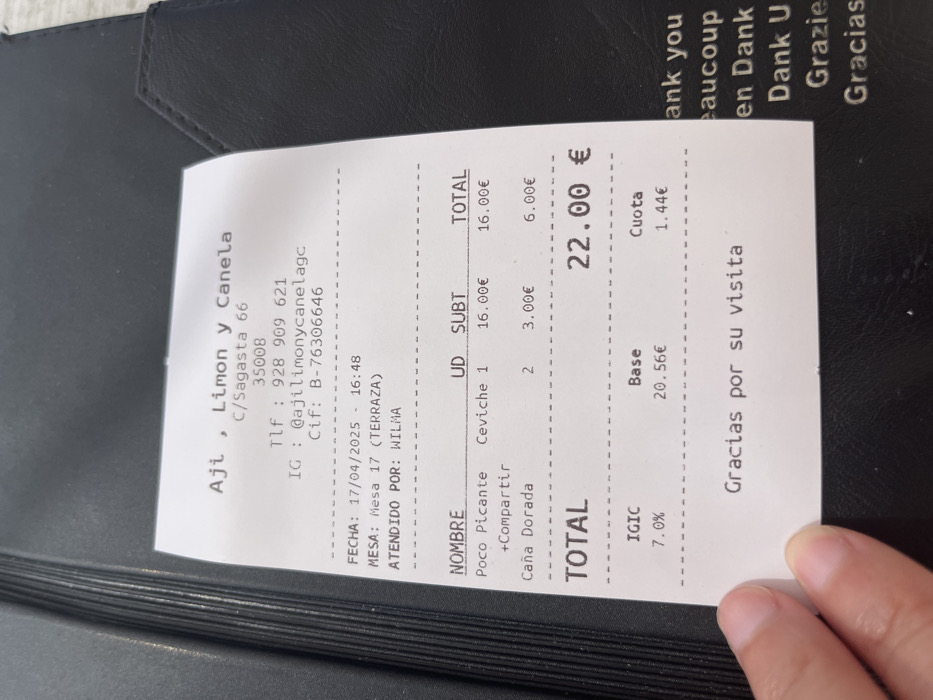 The image shows a receipt from a restaurant called Ají, Limón y Canela, located at C/Sagasta 66, 35008, Las Palmas de Gran Canaria, Spain. The coordinates provided place the restaurant in the neighborhood of Triana in the city of Las Palmas. The receipt details an order of one Ceviche for 16.00€ and two Caña Dorada for 6.00€, totaling 22.00€. The receipt was issued on 17/04/2025 at 16:48 to a table labeled "Mesa 17 (Terraza)" and was served by a person named "Wilma". The receipt also displays the restaurant's phone number, 928 909 621, Instagram account, @ajilimonycanelagc, and tax identification number, B-76306646. The receipt also shows the breakdown of the total amount, including the base price of 20.56€ and the VAT (IGIC) of 7.0%, which amounts to 1.44€. Finally, the receipt includes a thank you message in Spanish, English, French, German, and Italian. The receipt is held by a hand, obscuring part of the bottom.