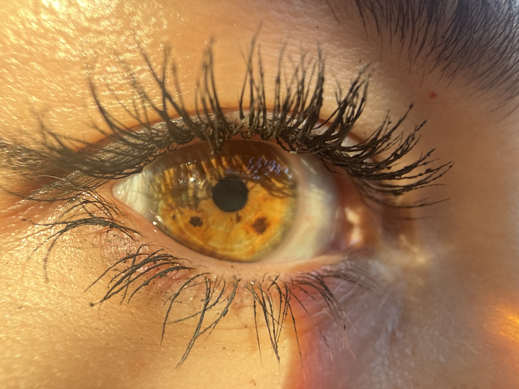 A close-up, high-resolution image shows a human eye with a golden iris and brown spots. The eyelashes are thick and black, and the skin surrounding the eye is fair. The lighting suggests an outdoor setting. There is no information about this image being in Sofia, Bulgaria.
