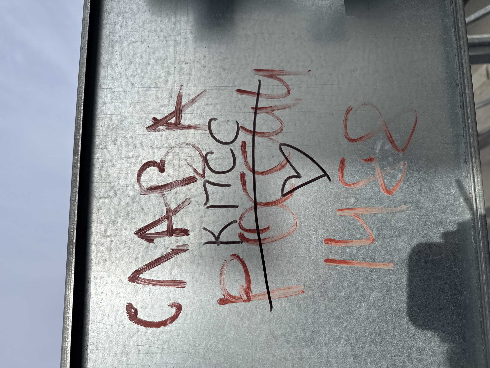 A close-up shot of a metallic surface, likely a support beam or panel. Red graffiti is scrawled on the metal. The graffiti includes the letters "CA" followed by a number "3" with a heart shape drawn in place of the last digit. Below this, the letters "KTC" are written, followed by "K17". The graffiti continues with a vertical line crossing out the letters and leading to a crude drawing of a heart. To the right, the numbers "14331" are written. The location is unknown and cannot be determined from this image.
