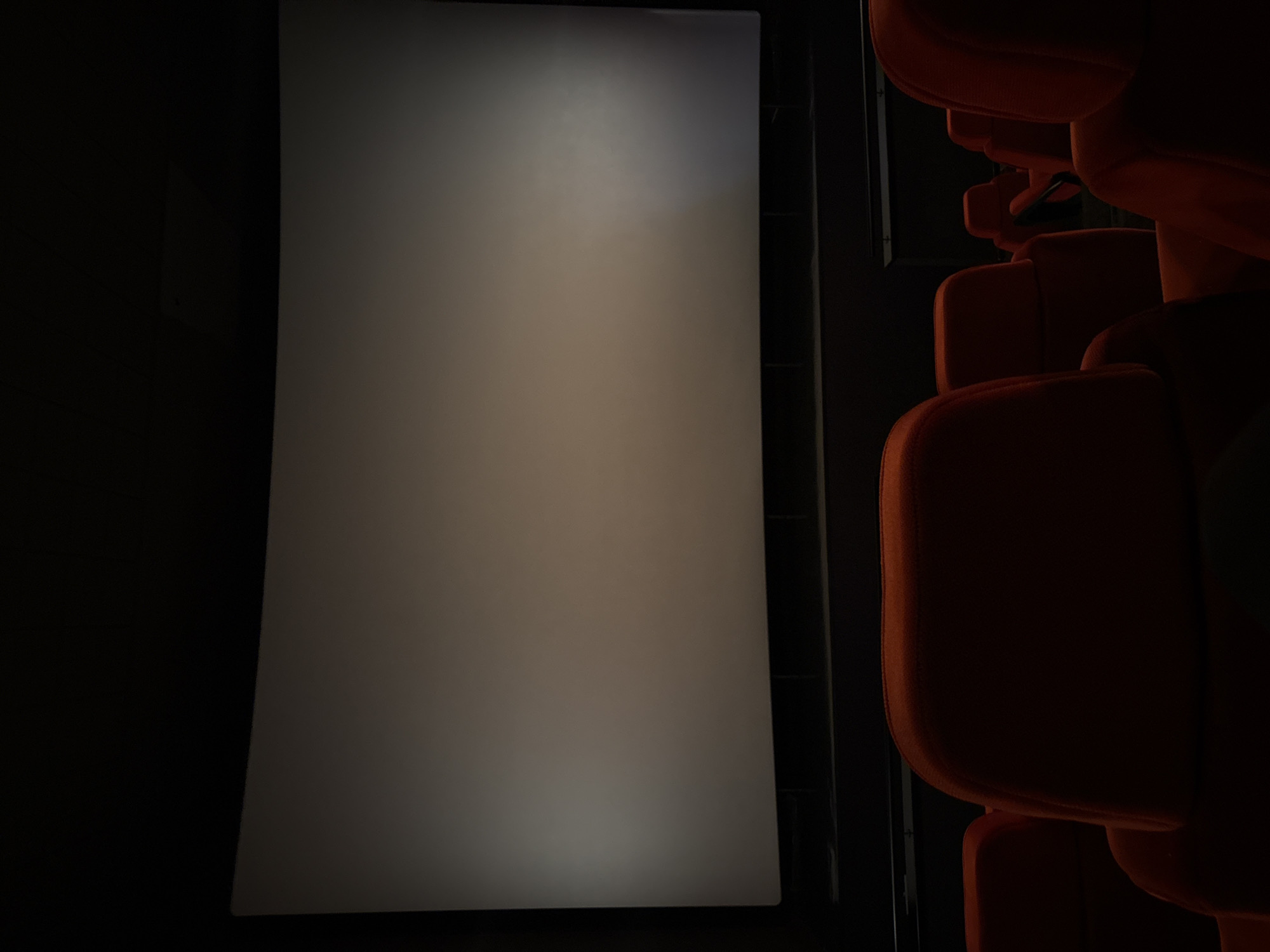 The image shows a movie screen in a darkened cinema. To the right of the screen are several rows of red theater seats. The location is likely a cinema in Plovdiv, Bulgaria.
