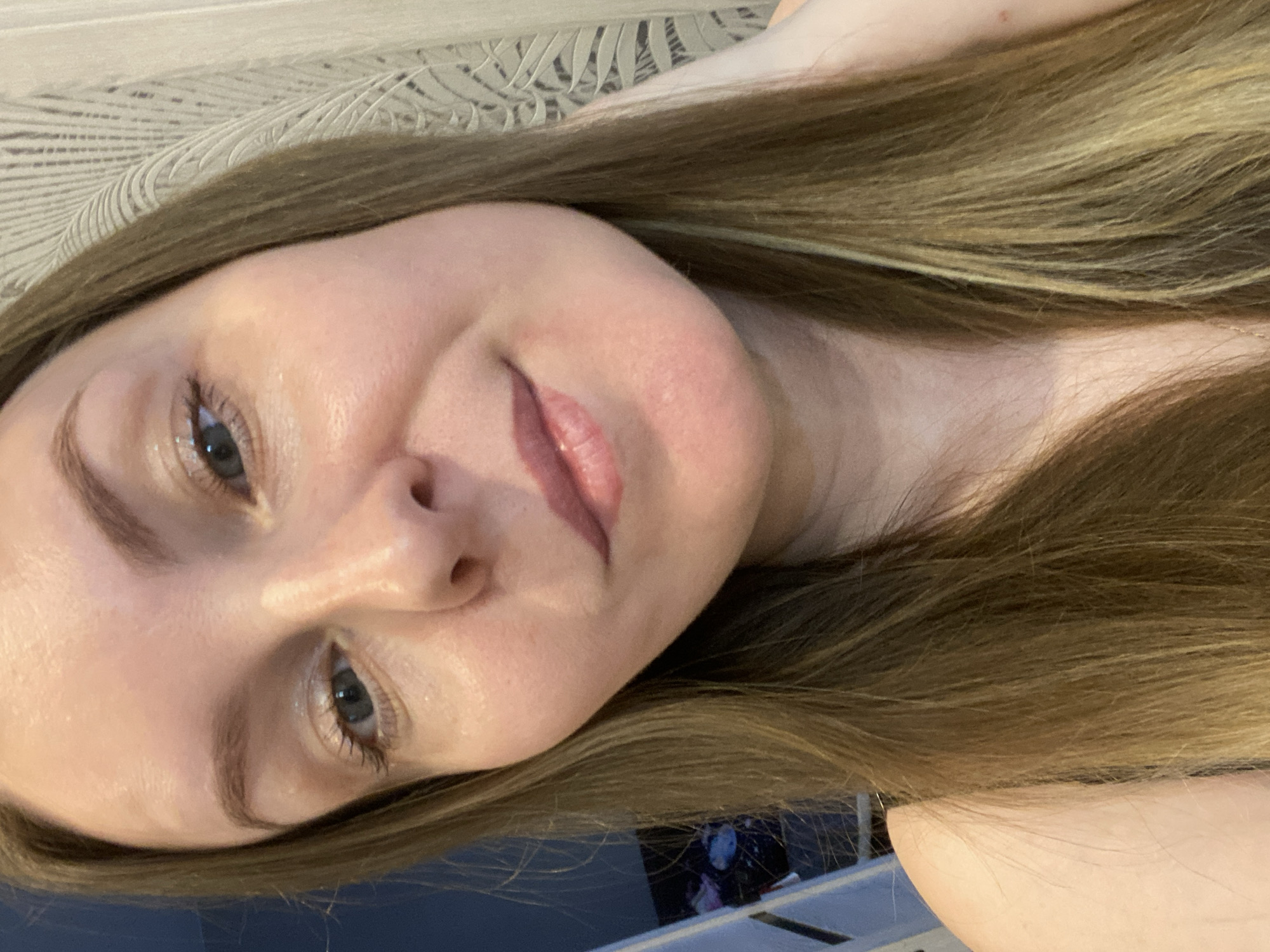 A fair-skinned woman with long, light brown hair is pictured. She is looking slightly down and to the left with a slight smile. Her eyes are blue. The background appears to be a textured surface. The woman is located in an unidentified location in the city of Noviy, Russia.