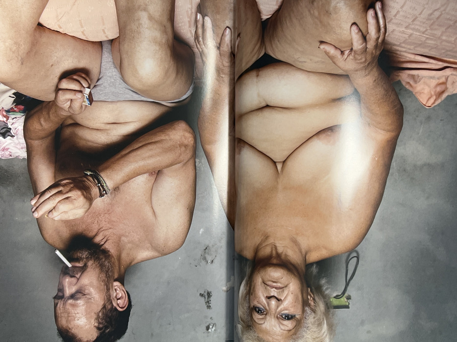 A photo captures two portraits positioned side by side, their orientation inverted. On the left, a man with a beard holds a cigarette. A bracelet adorns his wrist. He wears underwear. The right portrait showcases an older woman with white hair. The photo exposes their chests. The portraits reflect a raw, intimate portrayal of the human form, challenging conventional norms.