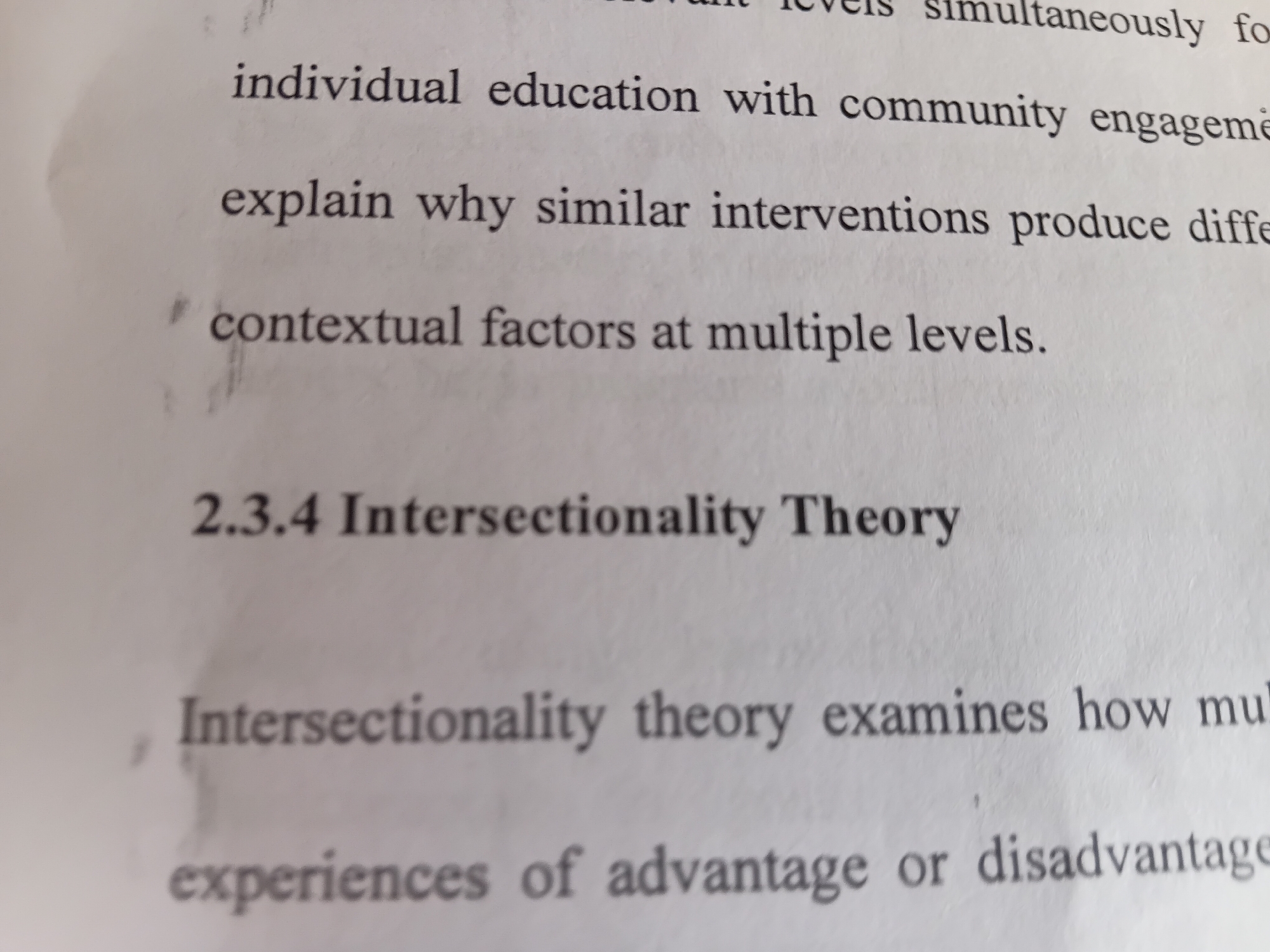 The image contains text on a white background. The text is oriented vertically, and appears to be from a book or document. The visible text fragments include "experiences of advantage or disadvantage", "Intersectionality theory examines how mul", "2.3.4 Intersectionality Theory", "contextual factors at multiple levels.", "explain why similar interventions produce diffe", and "individual education with community engageme". The image does not contain any geographical information that would allow for the identification of its location in Jalingo, Nigeria.