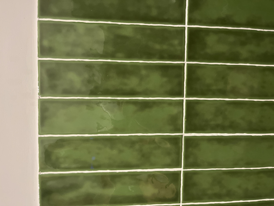 The image shows a wall tiled with dark green rectangular tiles, separated by thin white grout lines. The tiles are arranged in a grid pattern. The image was taken at coordinates 28.102 latitude, -15.415 longitude, which corresponds to a location in Las Palmas de Gran Canaria, Spain.