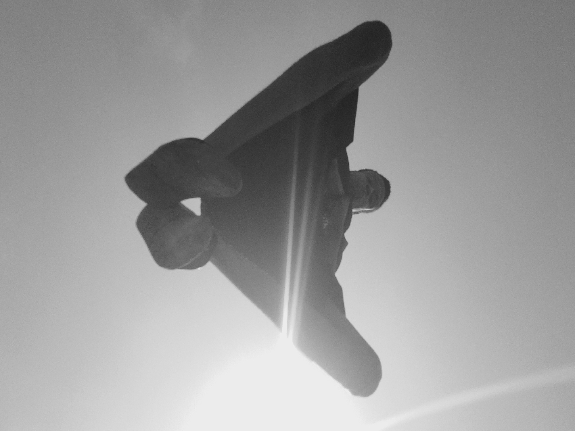 The image shows a low-angle view of a person standing in front of the sun. The sky is visible as the background. The person appears to be wearing shoes, pants, and a shirt or jacket. The sun is causing a lens flare effect. There is no other information to determine that it happened in the city of Narayi, Nigeria.