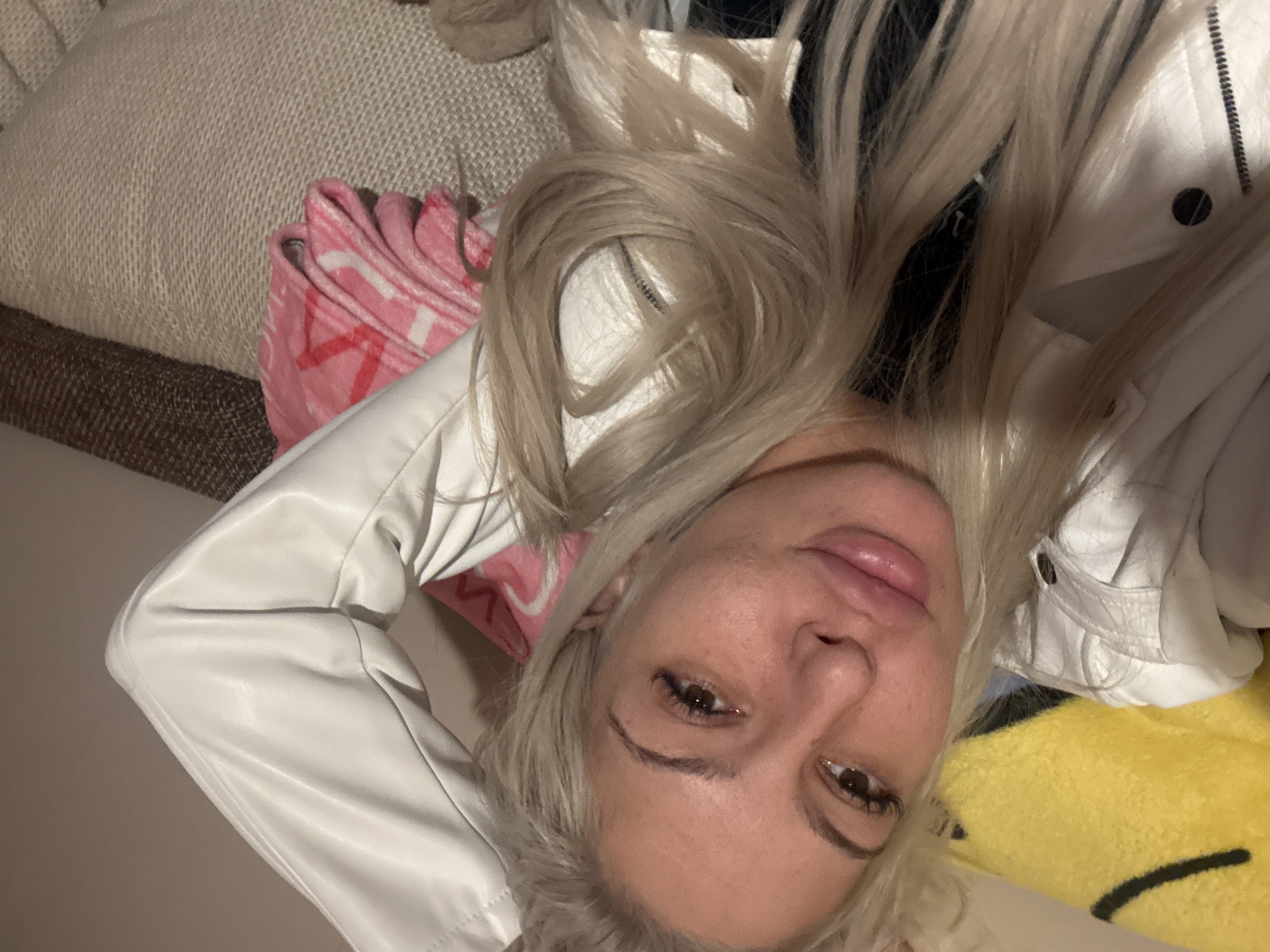 A woman with blonde hair is lying down, wearing a white jacket. There is a pink blanket and a yellow pillow beside her. The location in Plovdiv, Bulgaria is not discernible from this image.
