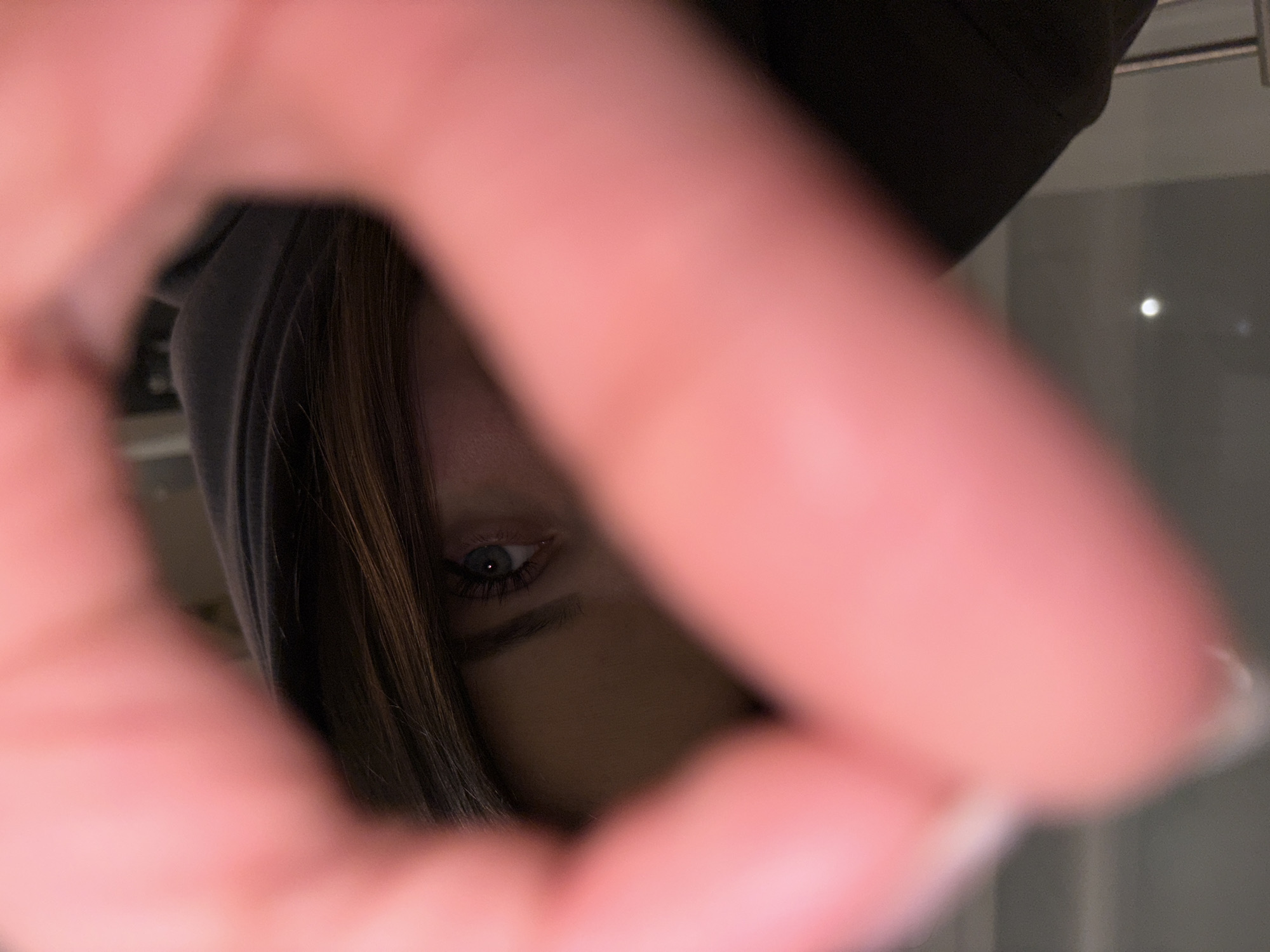 A close-up, obscured image shows a person's eye partially visible through a blurred circle created by fingers. The person has brown hair and is wearing a dark-colored hood. The background appears to be a nondescript interior space. There is no information available in the image to confirm any location, including the city of Chaikovsky, Russia.