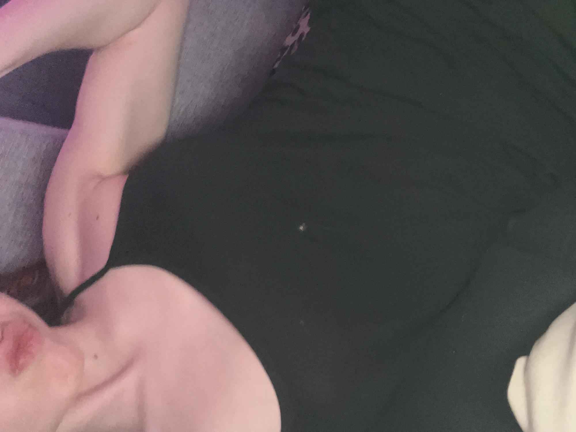 A person wearing a black top is lying on a gray upholstered surface. The person's left arm is raised and bent. Only the person's lips and neck are visible, suggesting a lying down position. The location is not identifiable as Saint Petersburg, Russia from the image alone.
