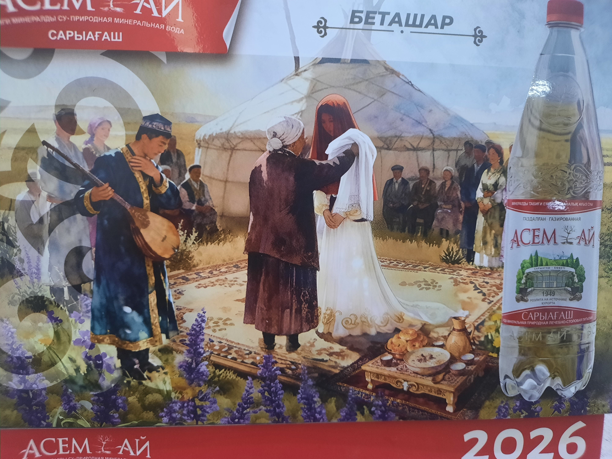 The image depicts a scene that appears to be an advertisement or promotional material related to a Kazakhstani brand. In the foreground, a bottle of "ACEM-AI" mineral water is prominently displayed on the right side. The bottle is clear and filled with water. The label on the bottle indicates that it is natural mineral water and mentions "Saryagash," a resort town in Kazakhstan known for its mineral springs.
The background features a cultural scene with several people dressed in traditional attire, gathered around a yurt, a nomadic dwelling. A man in a blue robe and a cap is playing a stringed instrument resembling a dombra. Two figures in the center, one in a brown garment and white headscarf and another in a white dress and red head covering, appear to be engaged in an interaction, possibly a ritual or ceremony. Other individuals are seated or standing in the background. A low table with food, including bread and bowls of what appears to be porridge, is set up in front of the central figures. The overall setting suggests a traditional or historical context, possibly emphasizing the natural origins of the mineral water.
The bottom of the image displays "ACEM-AI" again, along with the year "2026." The text "САРЫАГАШ" is visible on the water bottle and in other parts of the image, referring to the Saryagash resort. While the city of Zhanaozen, Kazakhstan is mentioned in the prompt, there are no specific visual elements within the image that directly identify it as being located in Zhanaozen. The scene focuses on the cultural and natural aspects associated with the Saryagash region.