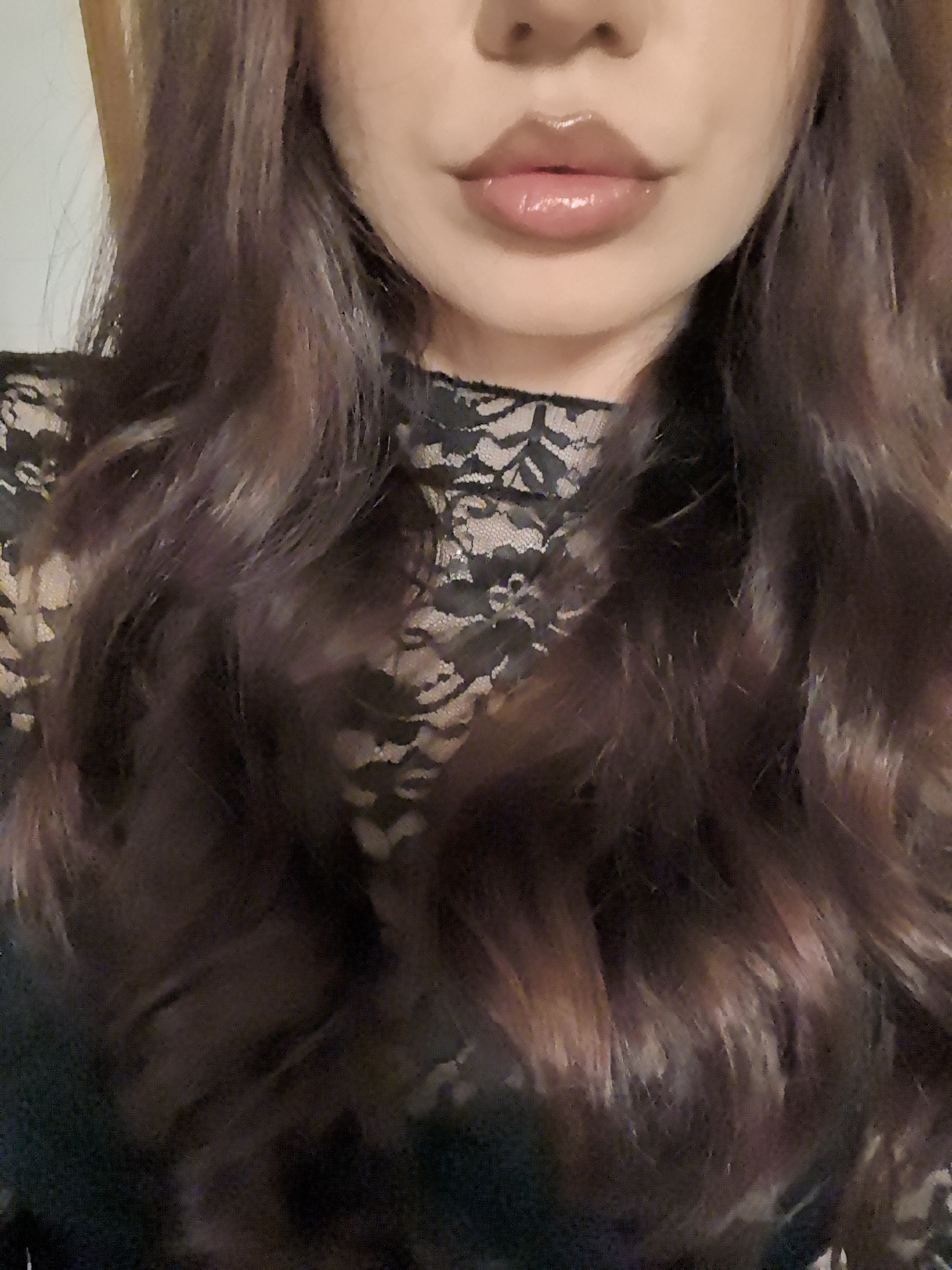A close-up shot of a woman's face, focusing on the lips, nose, and upper chest. The woman has dark hair that falls in loose waves around her shoulders. She wears a black lace top. The background is plain and out of focus. There is no indication of a specific location, particularly Stara Zagora, Bulgaria.