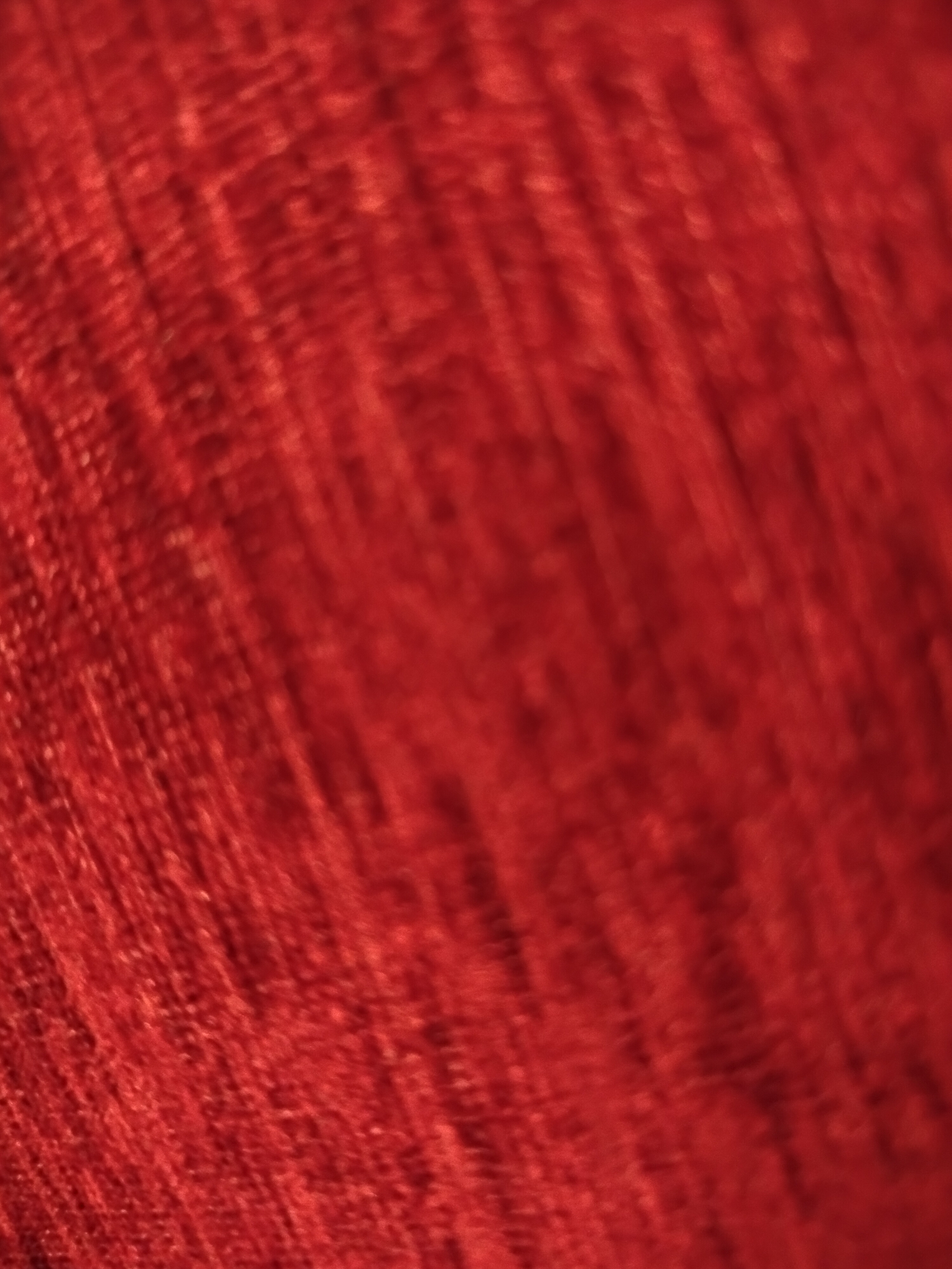 The image shows a close-up, blurred view of a textured, red fabric. There is no indication of location, people, subjects, objects, actions, interactions, or environment, so Yerevan, Armenia cannot be identified.