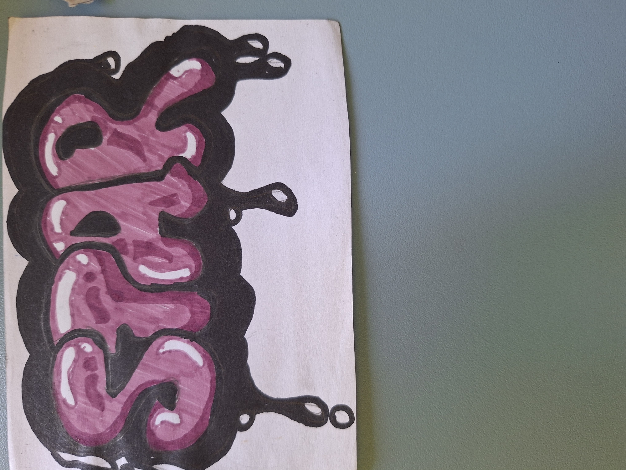 The image displays a close-up of a drawing featuring the word "SPAR" rendered in a graffiti style. The letters are filled with a glossy, purple-pink color and outlined in black, with white highlights to create a sense of volume. The word is enclosed within a black, cloud-like shape that appears to be dripping. The drawing is on a white piece of paper. The bottom portion of the image shows a textured, blue-gray wall. There is no information available to determine the location in the city of Varna, Bulgaria.