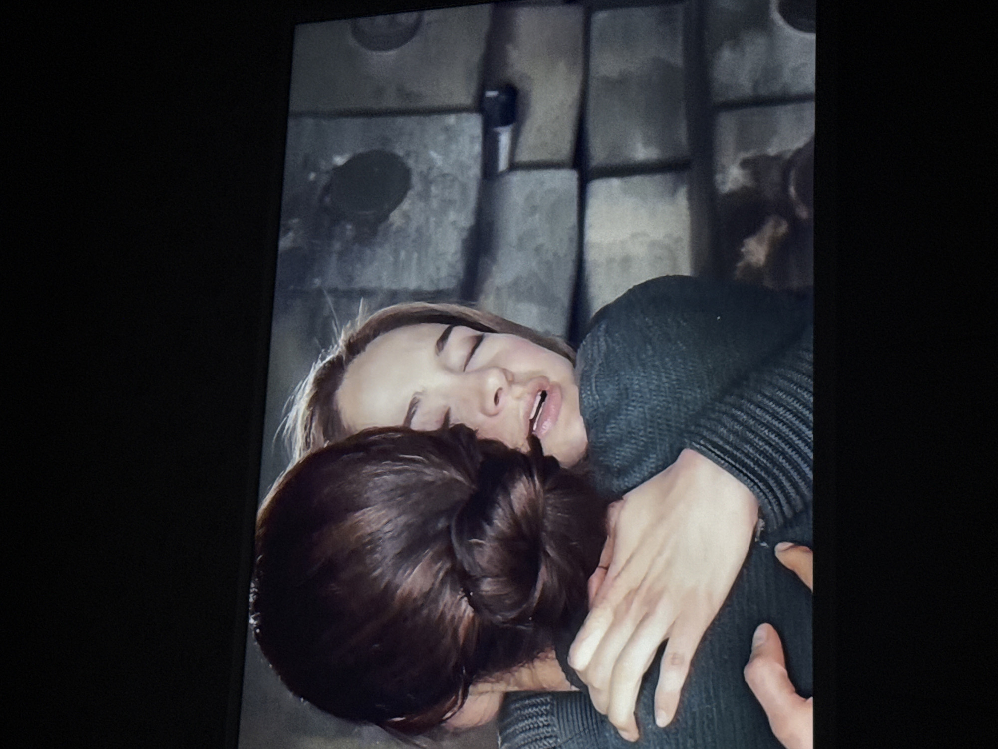 Two individuals are in close physical contact, apparently embracing. One individual has light-colored hair and is wearing a dark-colored, ribbed sweater. Their eyes are closed, and their mouth is slightly open. The other individual has dark hair pulled back in a bun. The location appears to be against a wall constructed of concrete blocks. The specific location within the city of Mytishchi, Russia cannot be determined from the provided image.