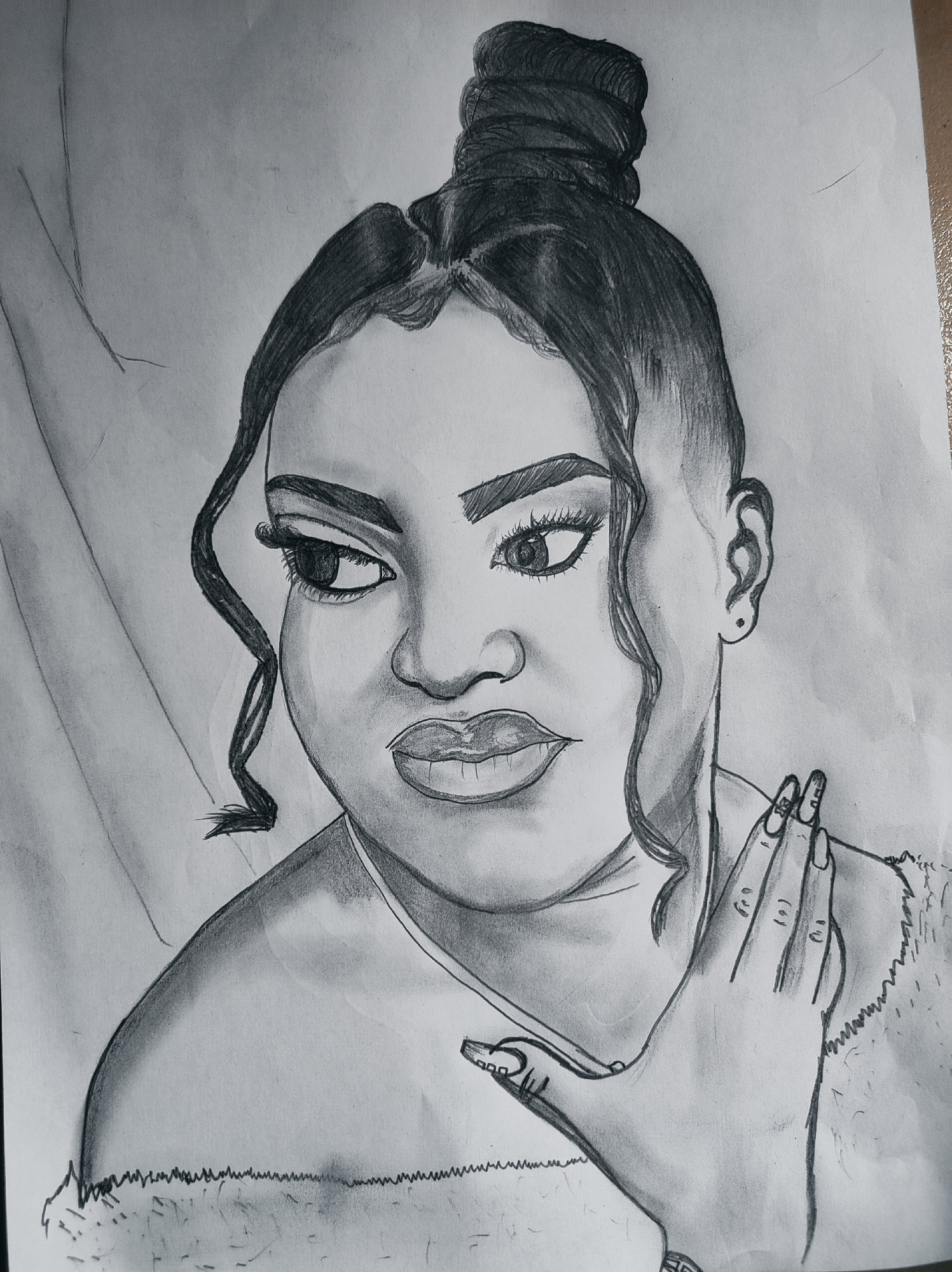 The image is a black and white pencil drawing of a woman. She is depicted with a high bun hairstyle, featuring curly strands framing her face. She has detailed eyebrows, eyes with eyelashes, a nose, and full lips. The woman's right hand is raised towards her face, and her fingernails are long with painted designs. She appears to be wearing a fur-trimmed garment. The background is plain and slightly shaded. The image does not include any contextual information that would allow determining a location in Abuja, Nigeria.