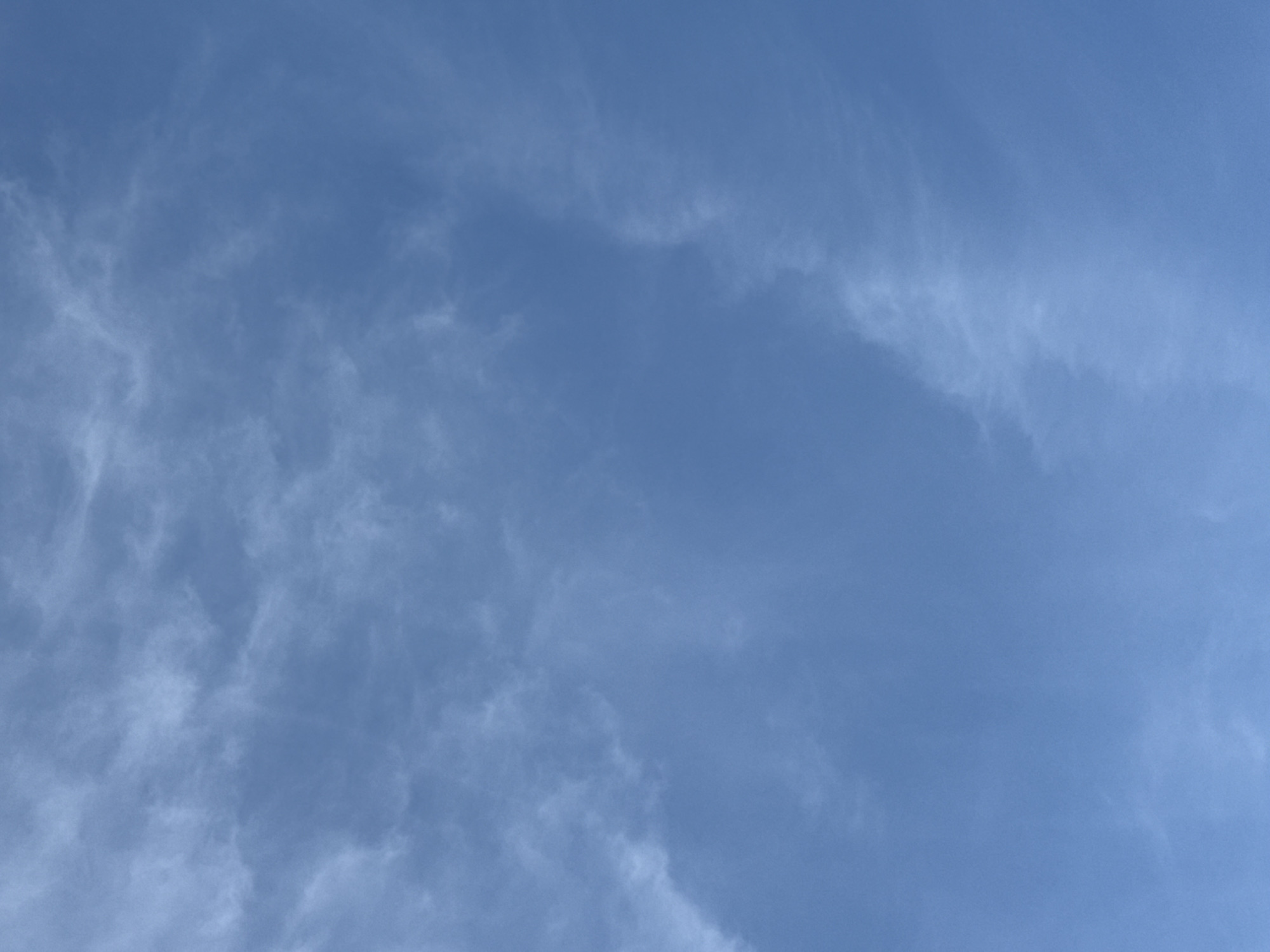 The image shows a daytime view of a light blue sky with sparse, wispy white clouds. The cloud formation is more concentrated on the left side of the image, gradually thinning out towards the right. There is no evidence to suggest this image was taken in Votkinsk, Russia. No people, subjects, objects, actions, or interactions are visible.