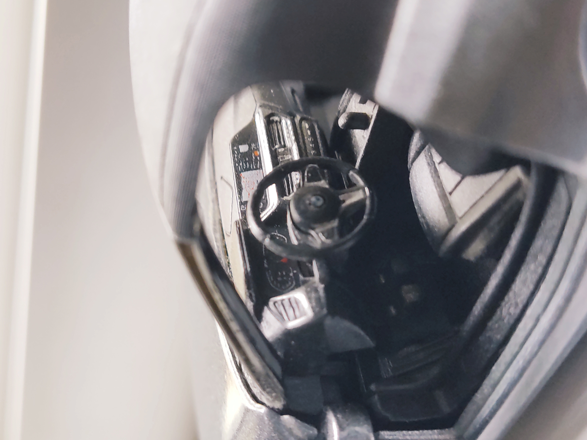 The image shows the interior of a car, specifically the dashboard and steering wheel. The steering wheel has a BMW logo on it. The dashboard is visible with some gauges and displays. The interior appears to be black or dark gray. The photo appears to have been taken at close range with a shallow depth of field, obscuring the surrounding environment. The location is not discernible from the image.