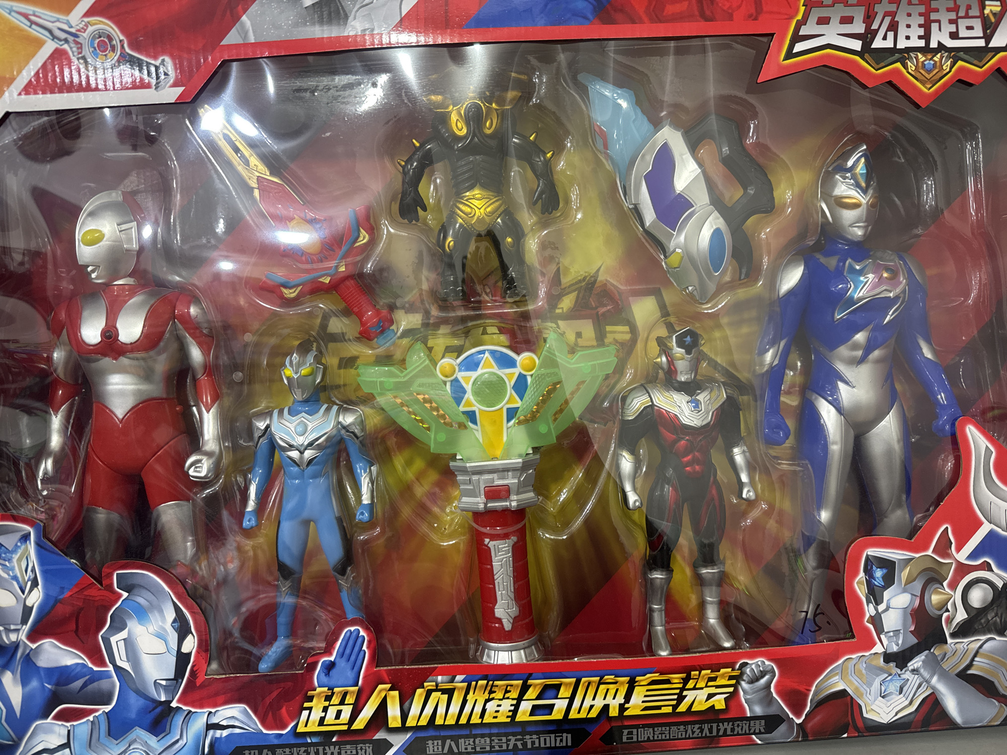 The image shows a boxed set of Ultraman action figures. The figures are various colors, including red, blue, silver, and black. The set also includes accessories such as a sword, a shield, and a pedestal-like object. The packaging has Chinese text and imagery of Ultraman characters. The image was taken in the city of Zhongtun, China.