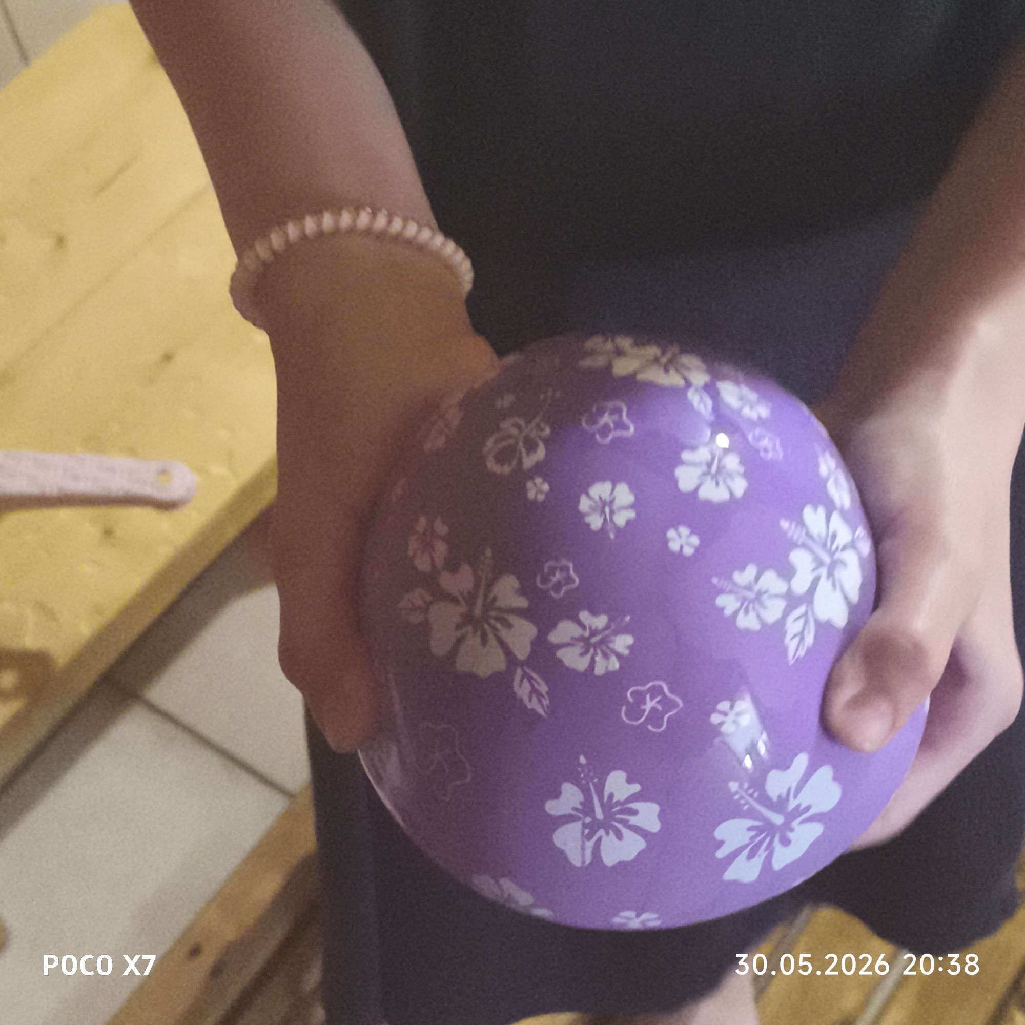 A person is holding a purple balloon with white flower prints. The person is wearing a dark-colored garment and a bracelet. The photo was taken with a POCO X7 device. The date and time stamp on the image indicates 30.05.2026 20:38. No specific location in the city of Chaikovsky, Russia is discernible from the provided image.