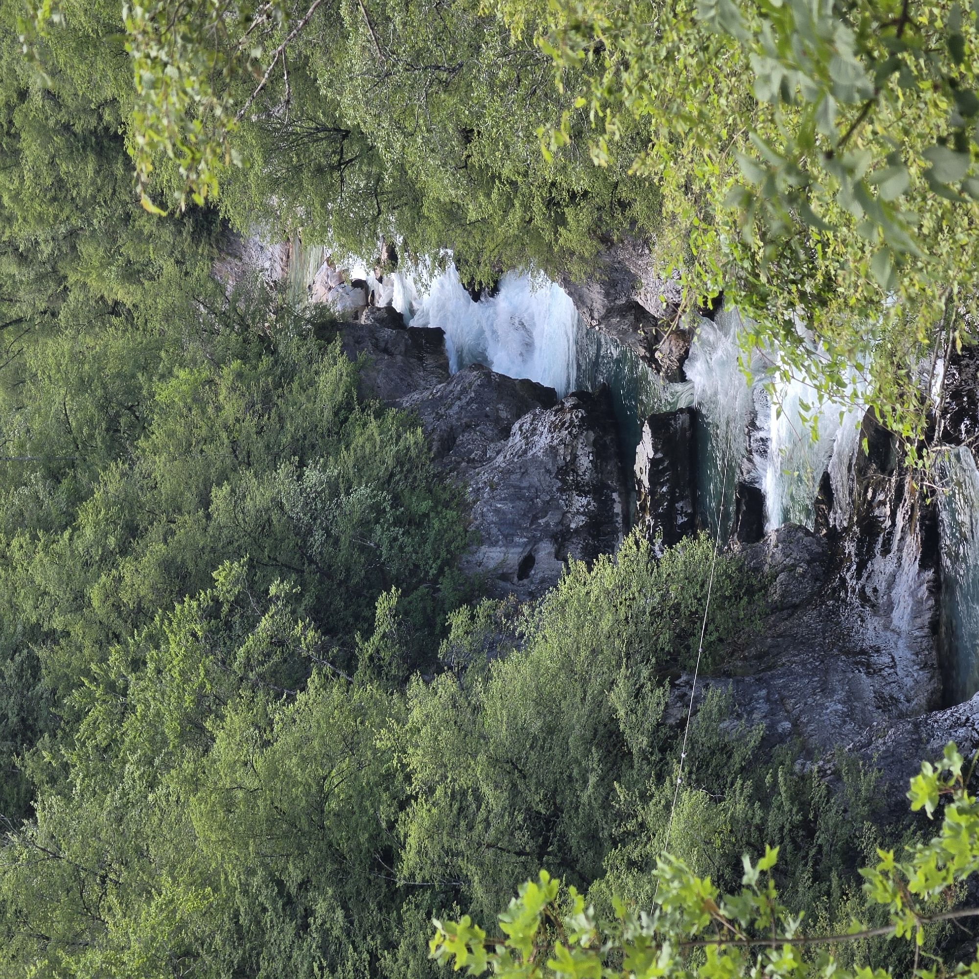 A verdant forest surrounds a cascading river, revealing a rocky riverbed with clear, rushing water. The location is Međuriječje, Montenegro.